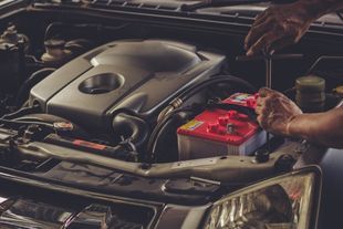 A man is working on the engine of a car with a wrench.