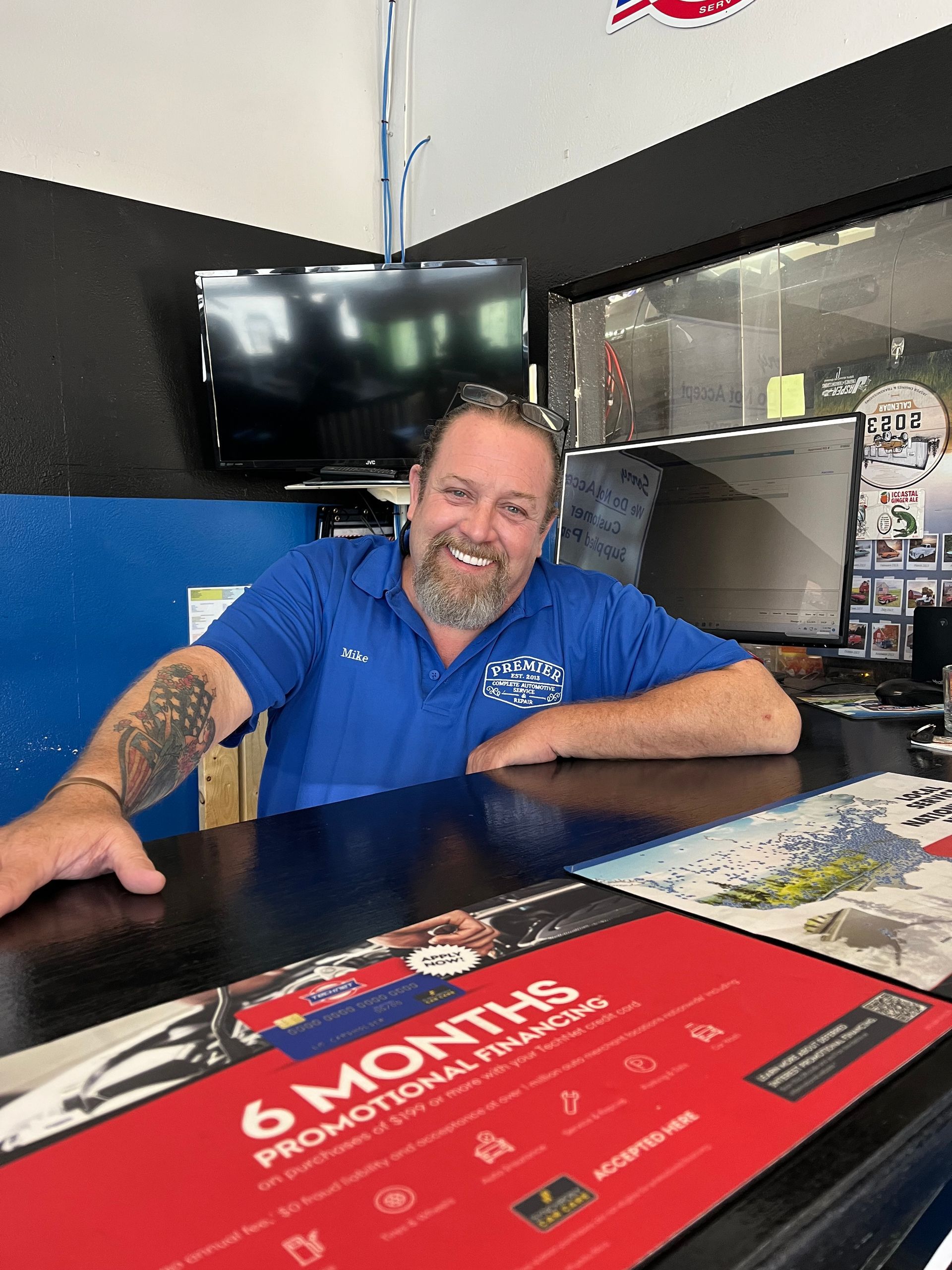 A man is sitting at a counter in a car dealership.
