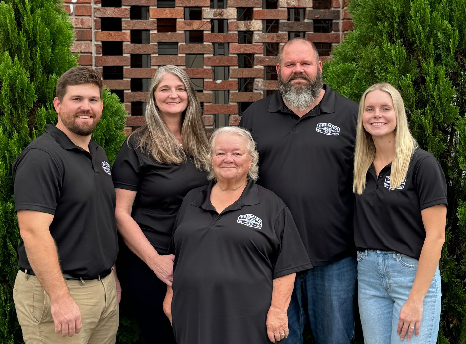 A group of people are posing for a picture in front of a brick wall.