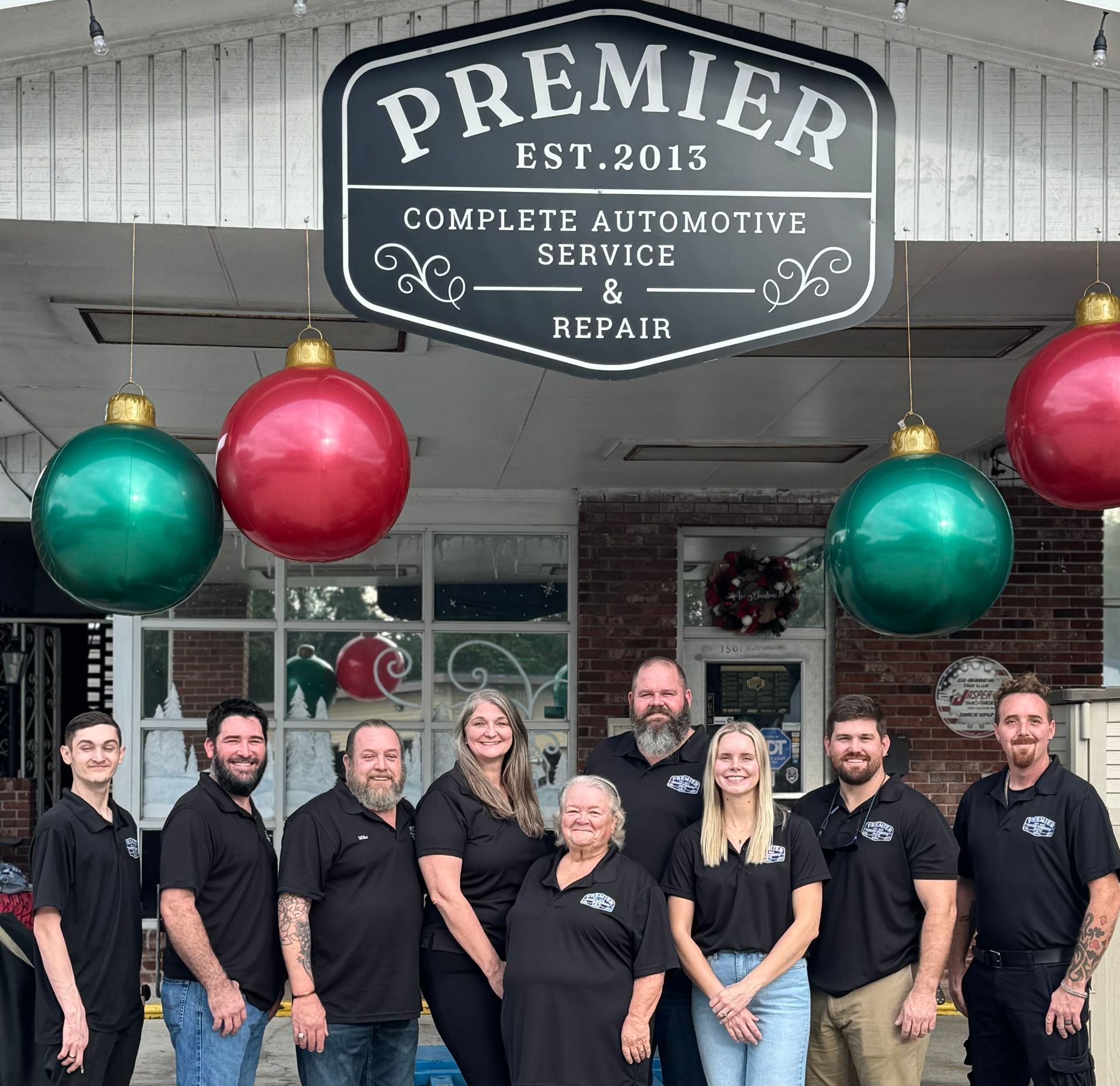 A group of people standing in front of a premier complete automotive service and repair sign