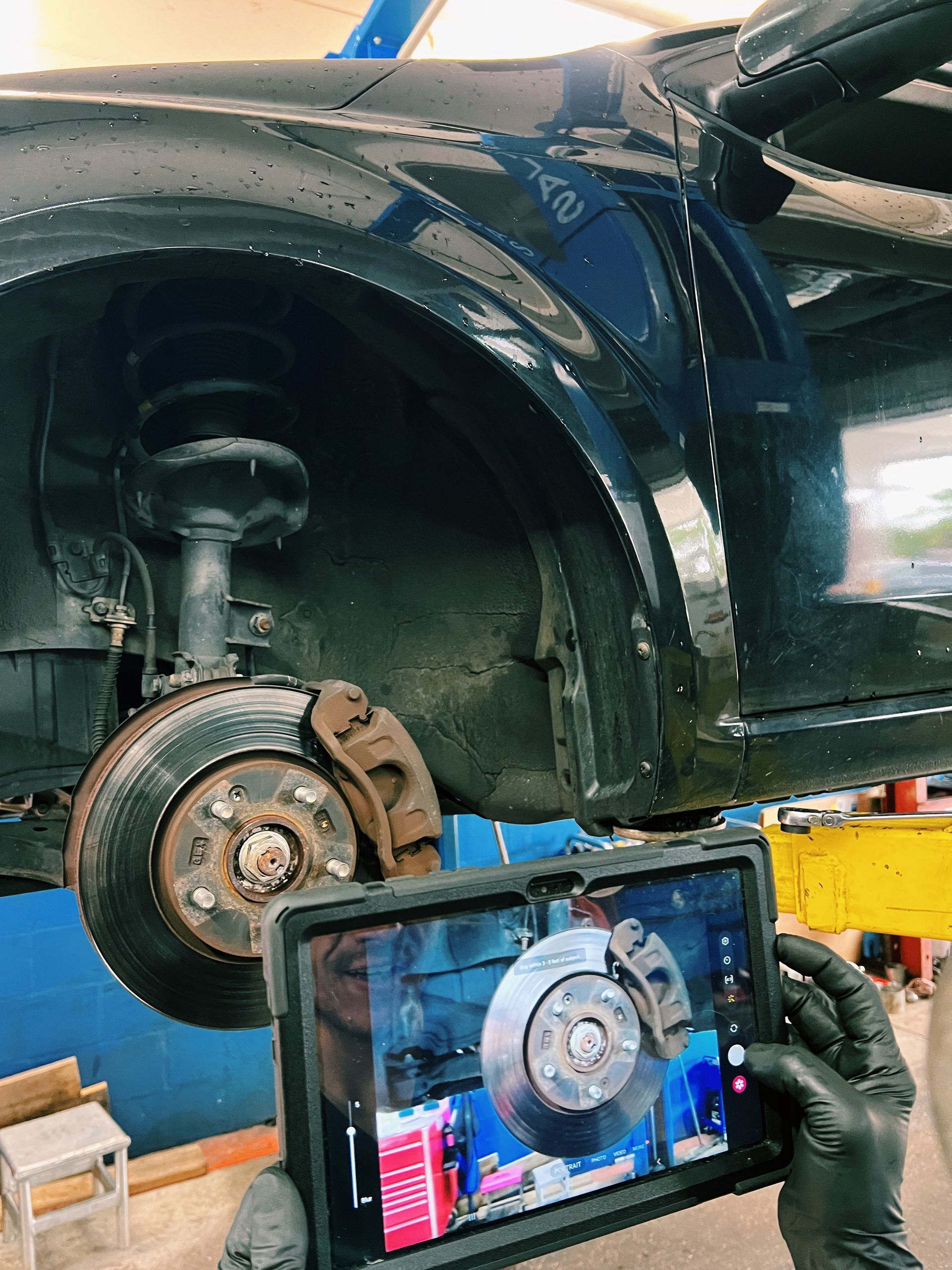 A person is taking a picture of a car with a tablet.