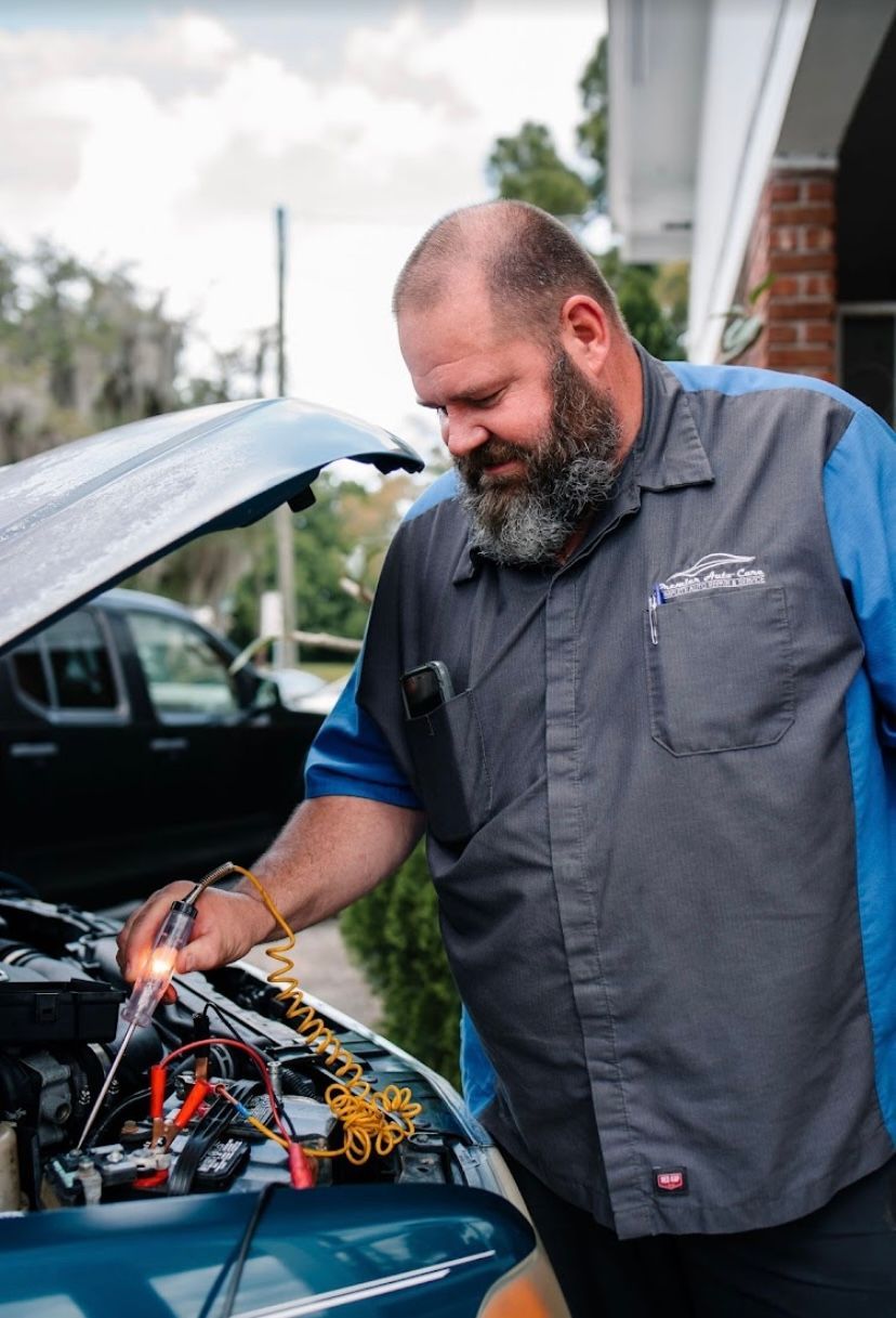 A man with a beard is working on a car with the hood open.
