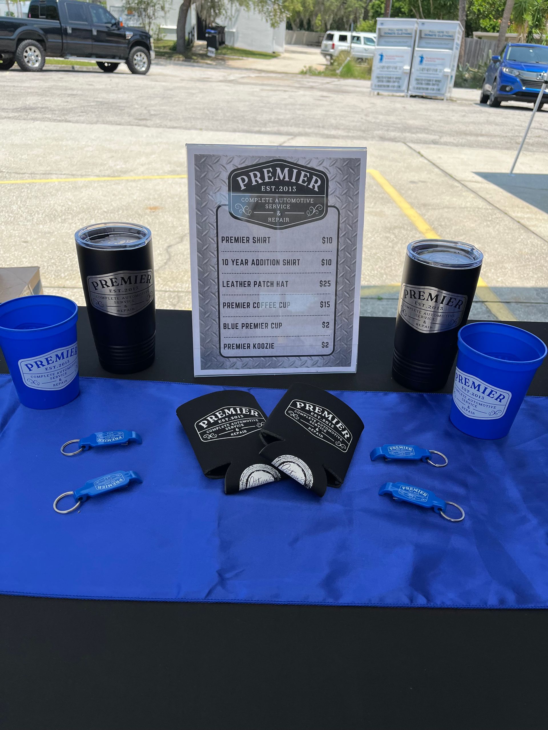 A table with blue cups , keychains , and a sign on it.