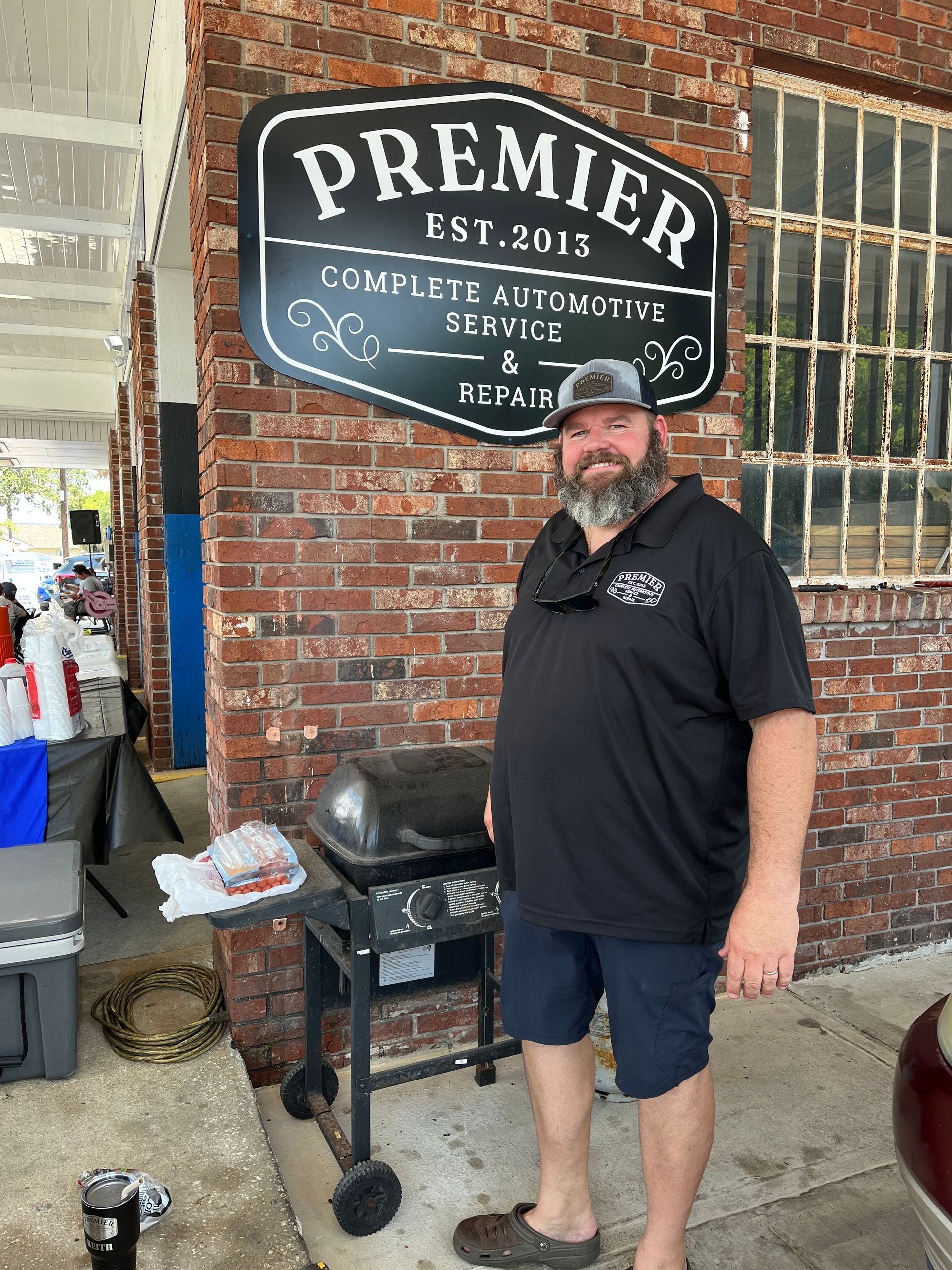 A man with a beard is standing in front of a premier sign.