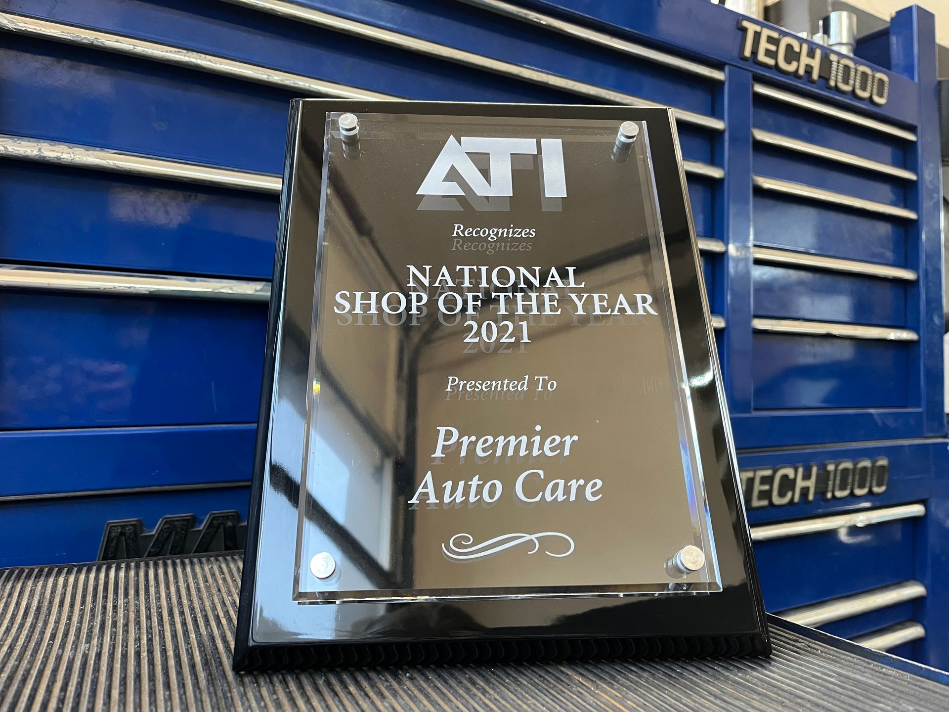 A national shop of the year plaque is sitting on a table in front of a blue toolbox.