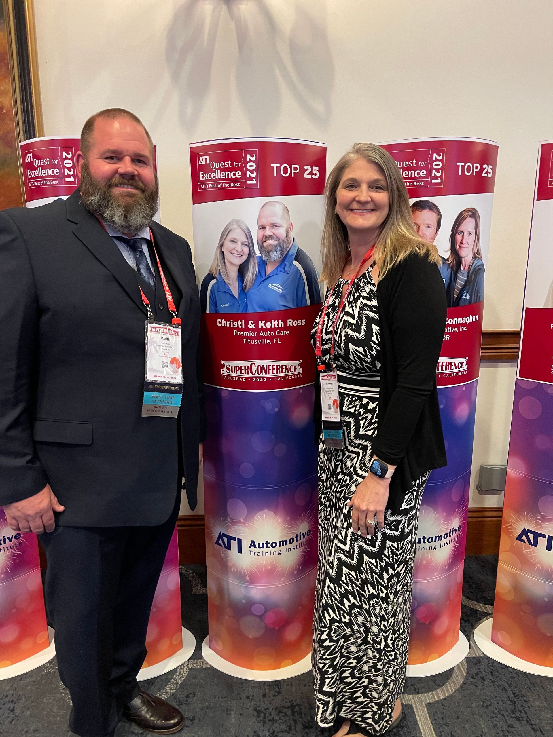 A man and a woman are standing next to each other in front of a row of signs.