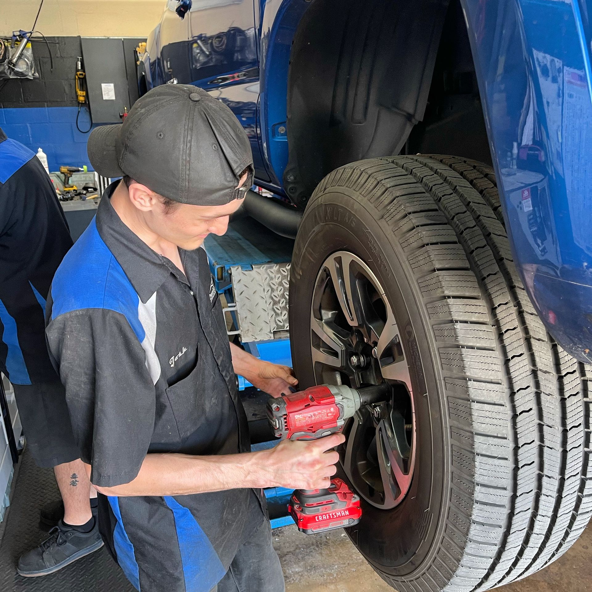 A man is working on a tire on a blue truck