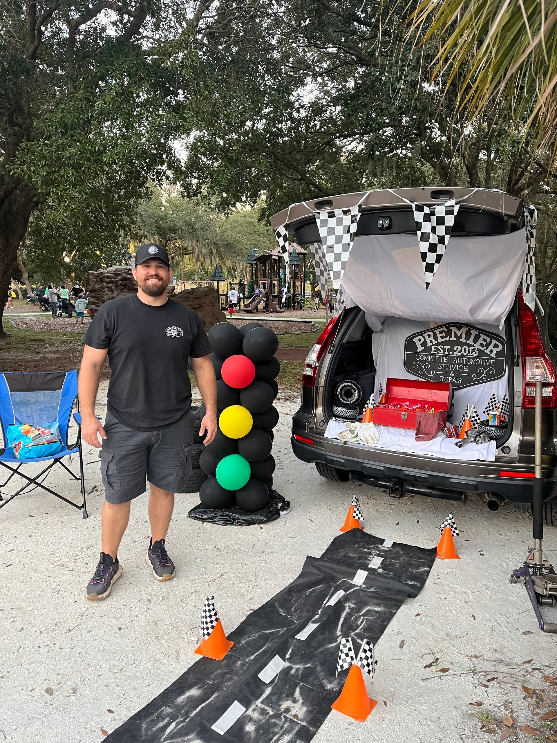 A man is standing in front of a trunk decorated for a trunk or treat.