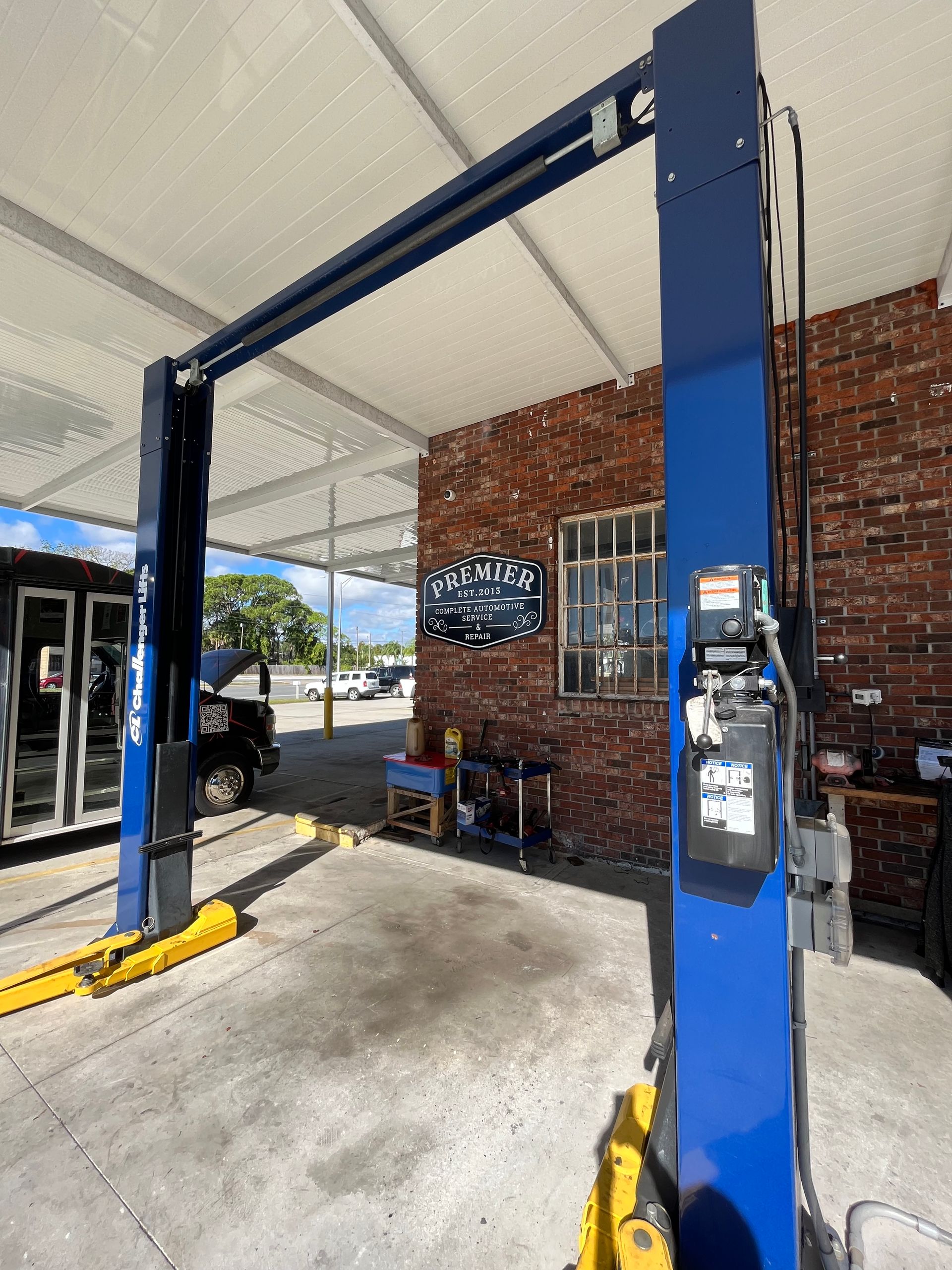A blue car lift is sitting in front of a brick building.