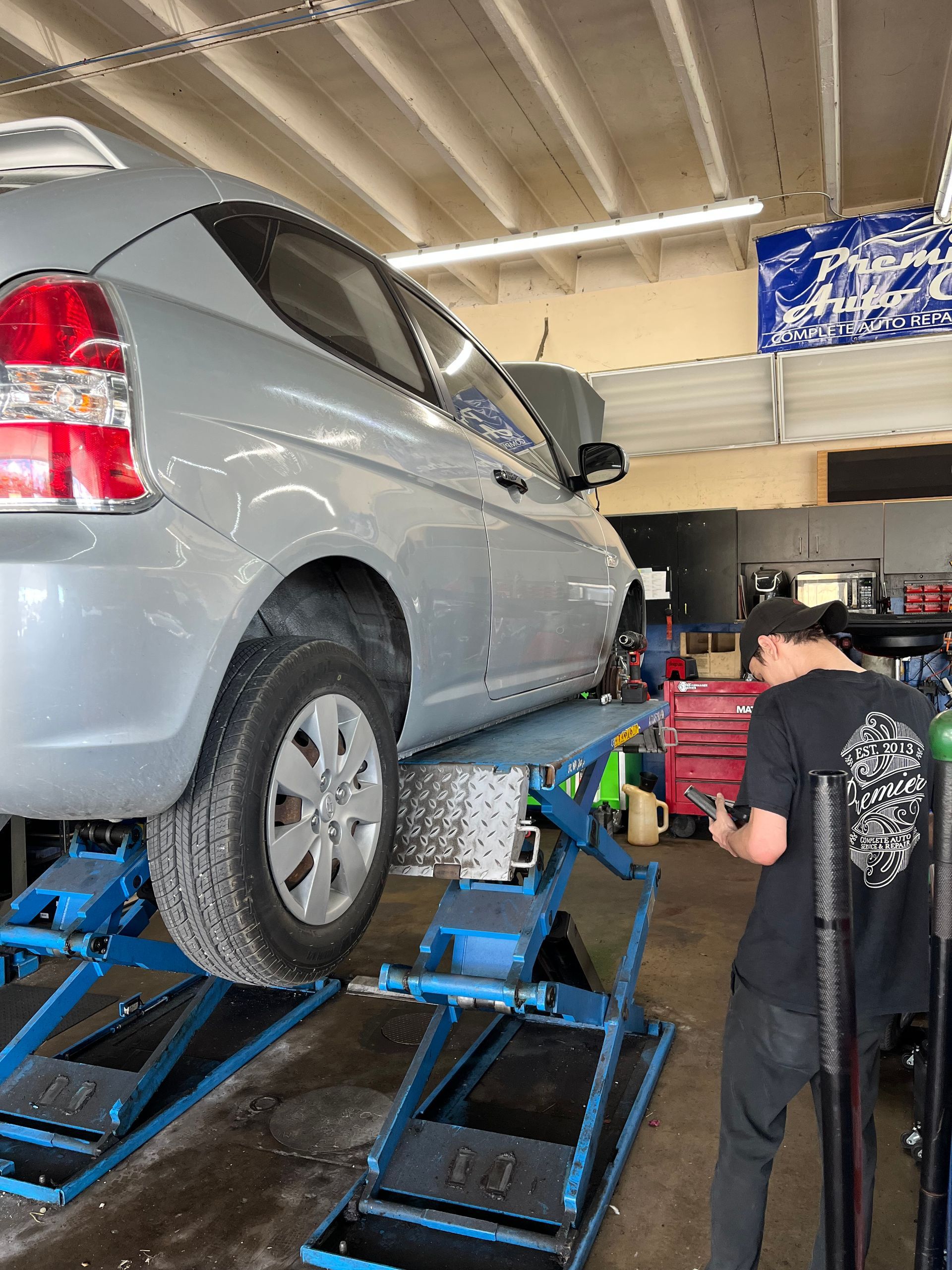 A man is working on a car on a lift in a garage.