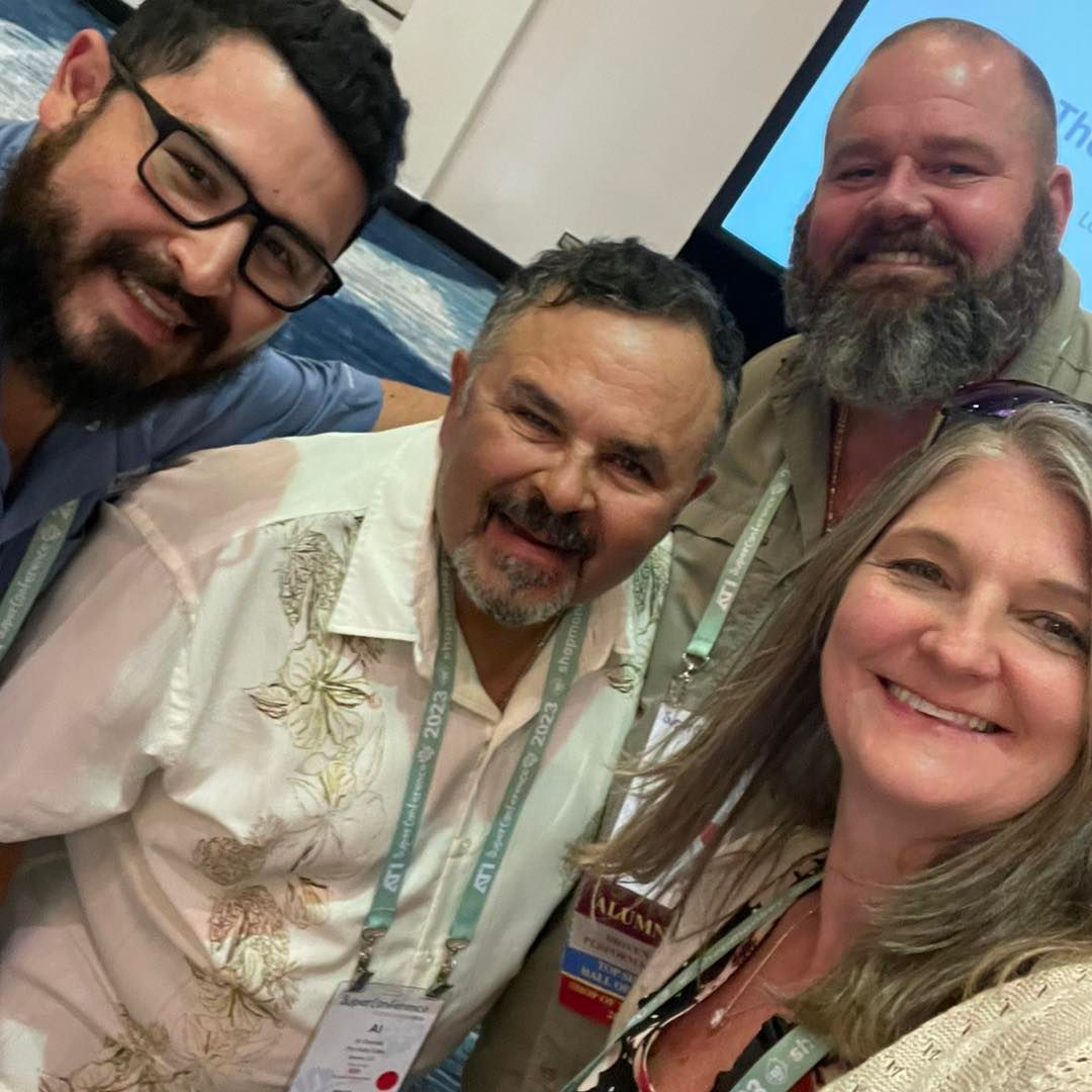 A group of people posing for a picture with one woman wearing a lanyard that says ' allianz ' on it