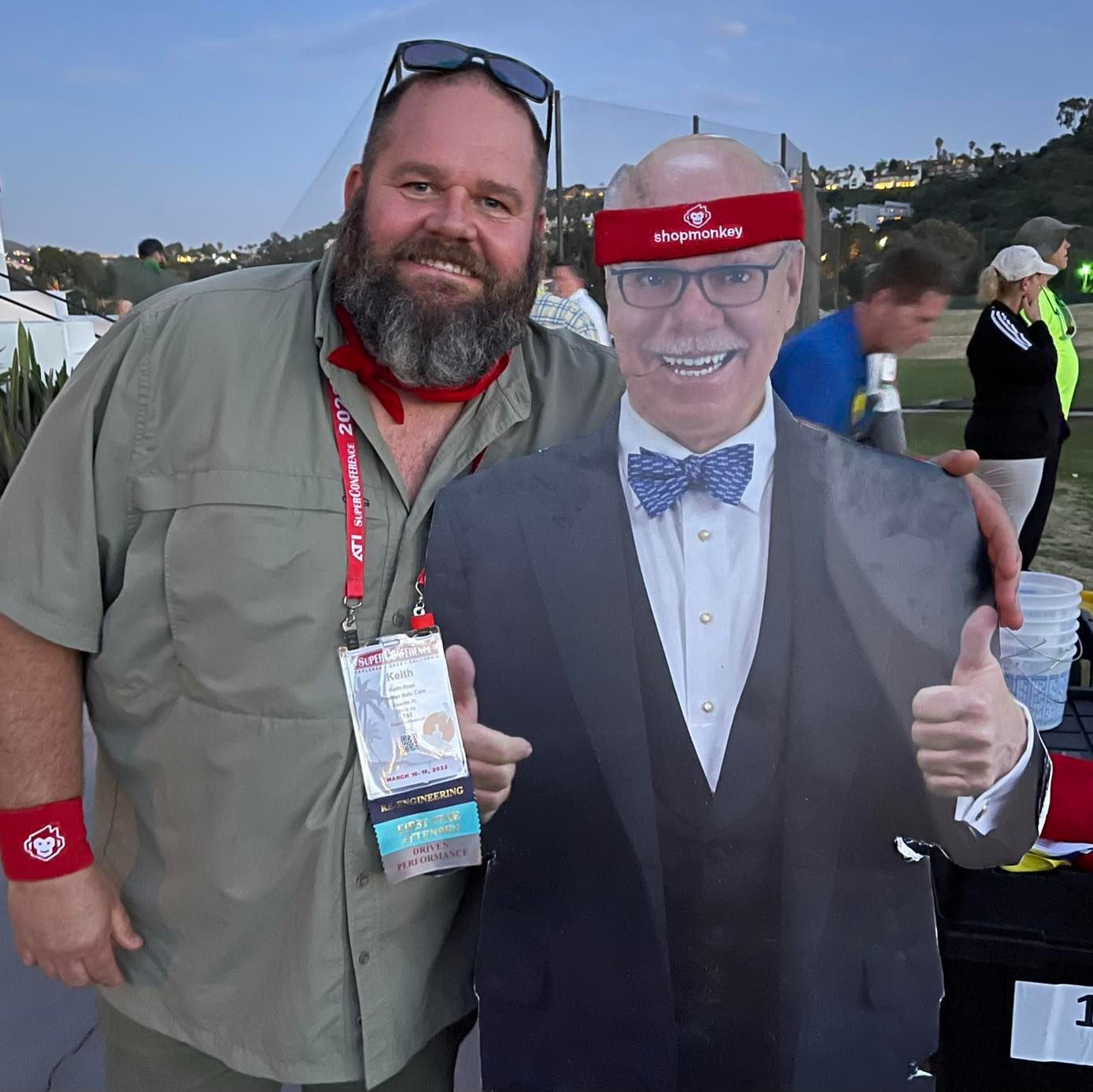A man standing next to a cardboard cutout of a man in a suit and bow tie