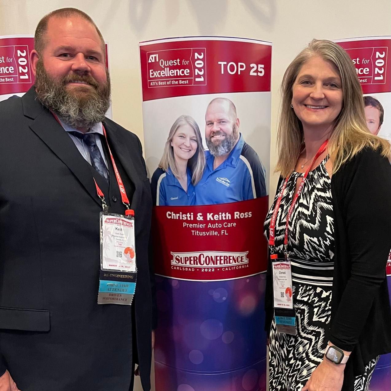 Two people standing in front of a sign that says top 25