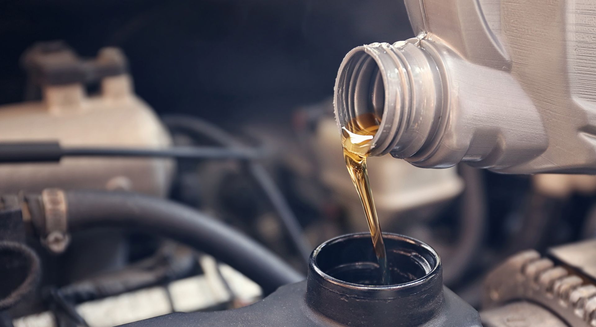 A bottle of oil is being poured into a car engine.