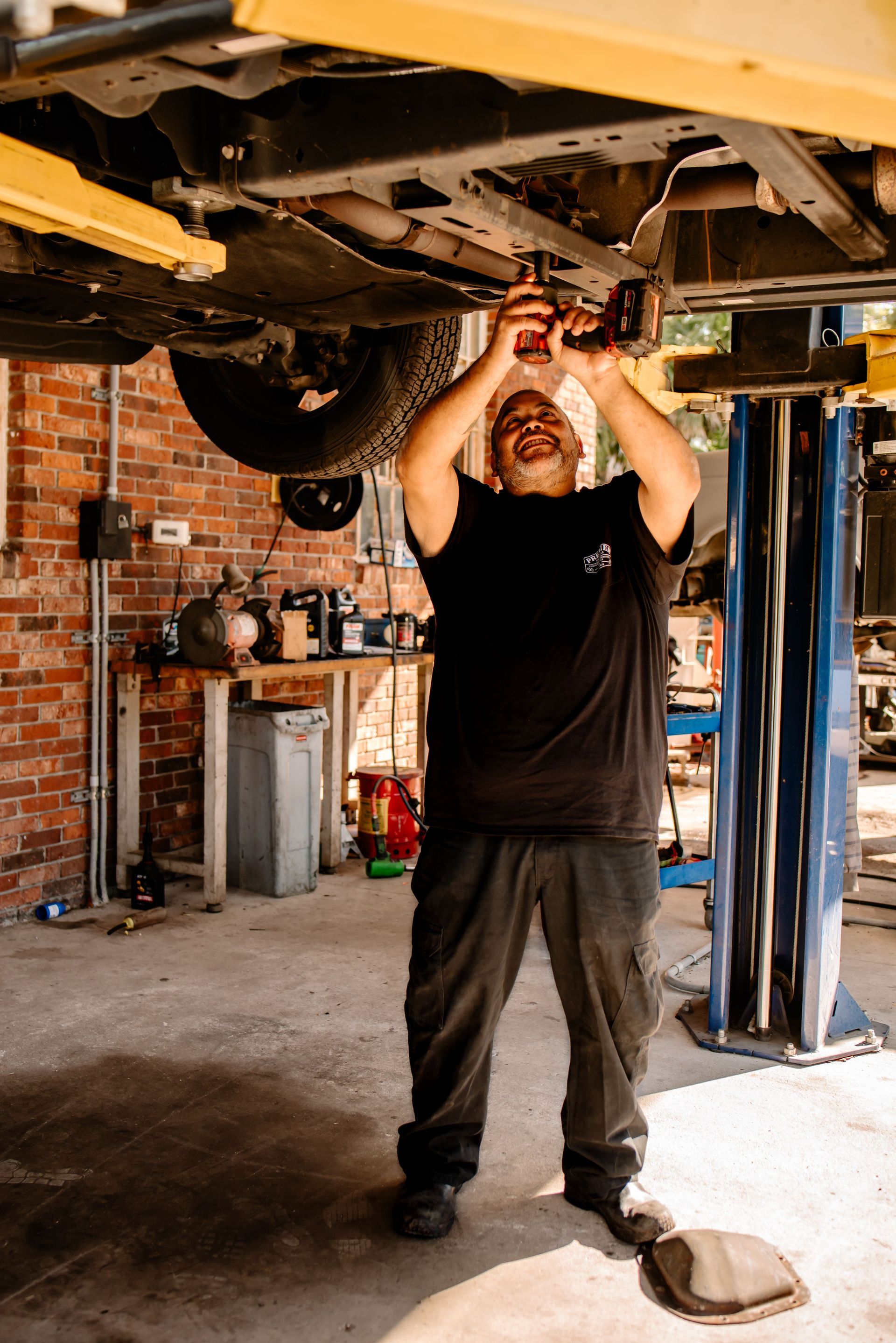 Two men are standing next to each other in front of a brick wall.