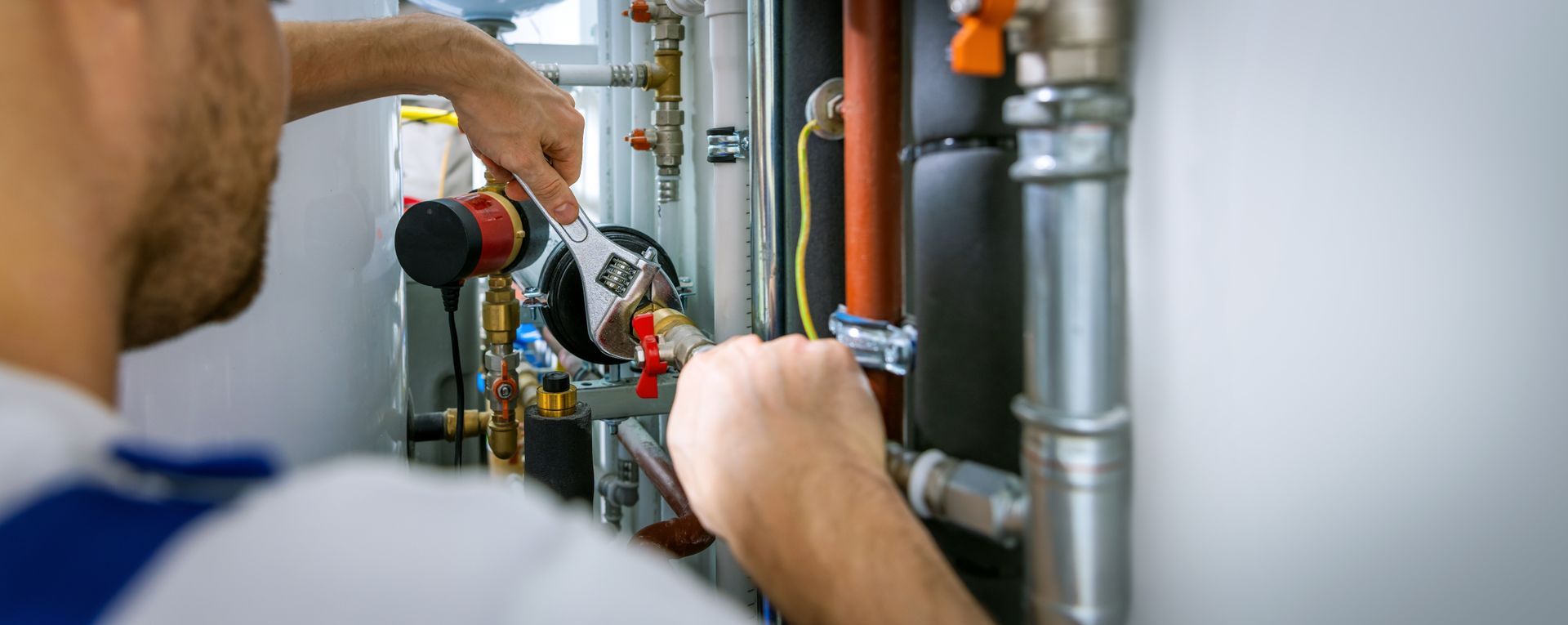 A plumber tightening pipe fittings with a wrench
