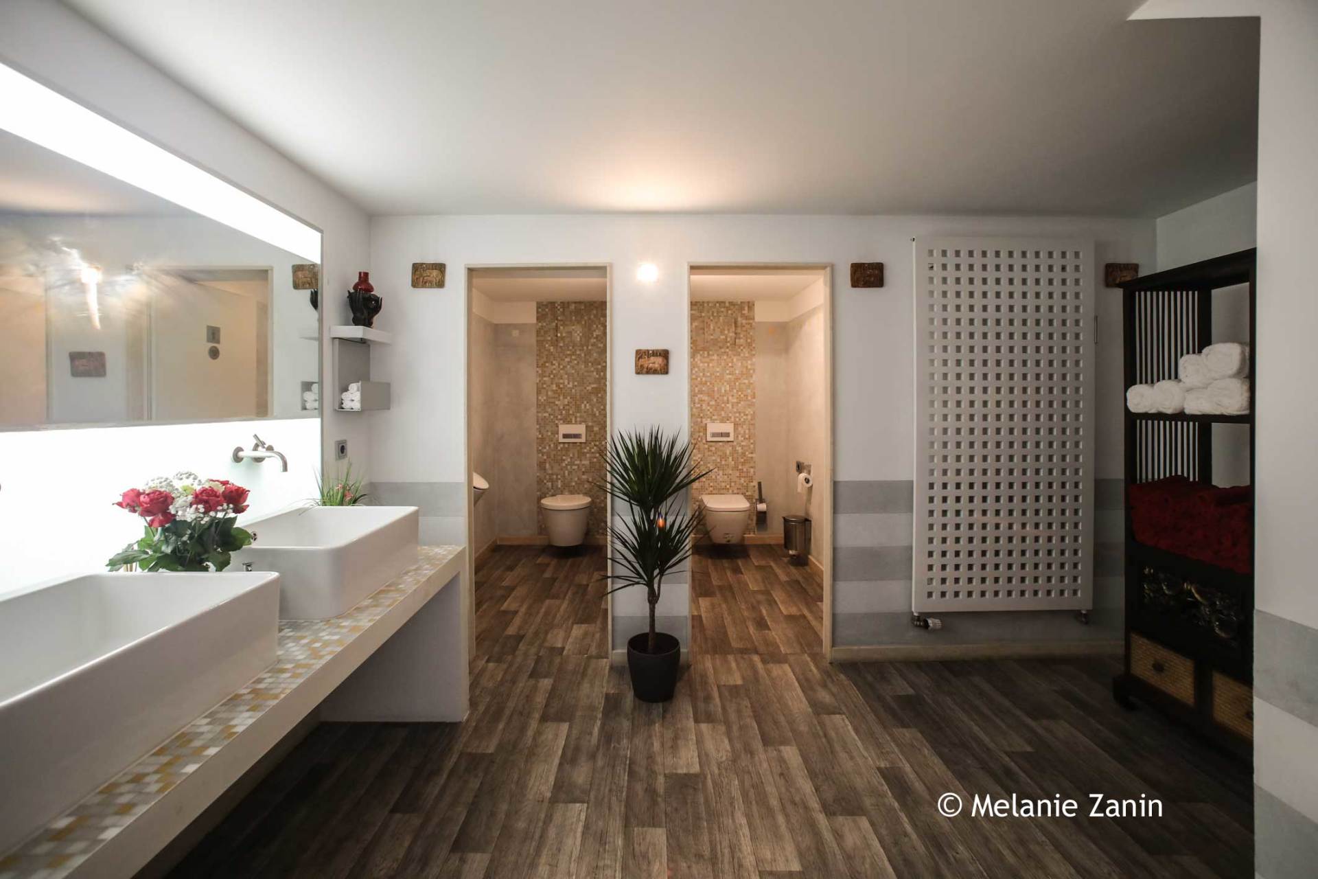 Ein Badezimmer mit zwei Waschbecken, einer Toilette und einer Pflanze