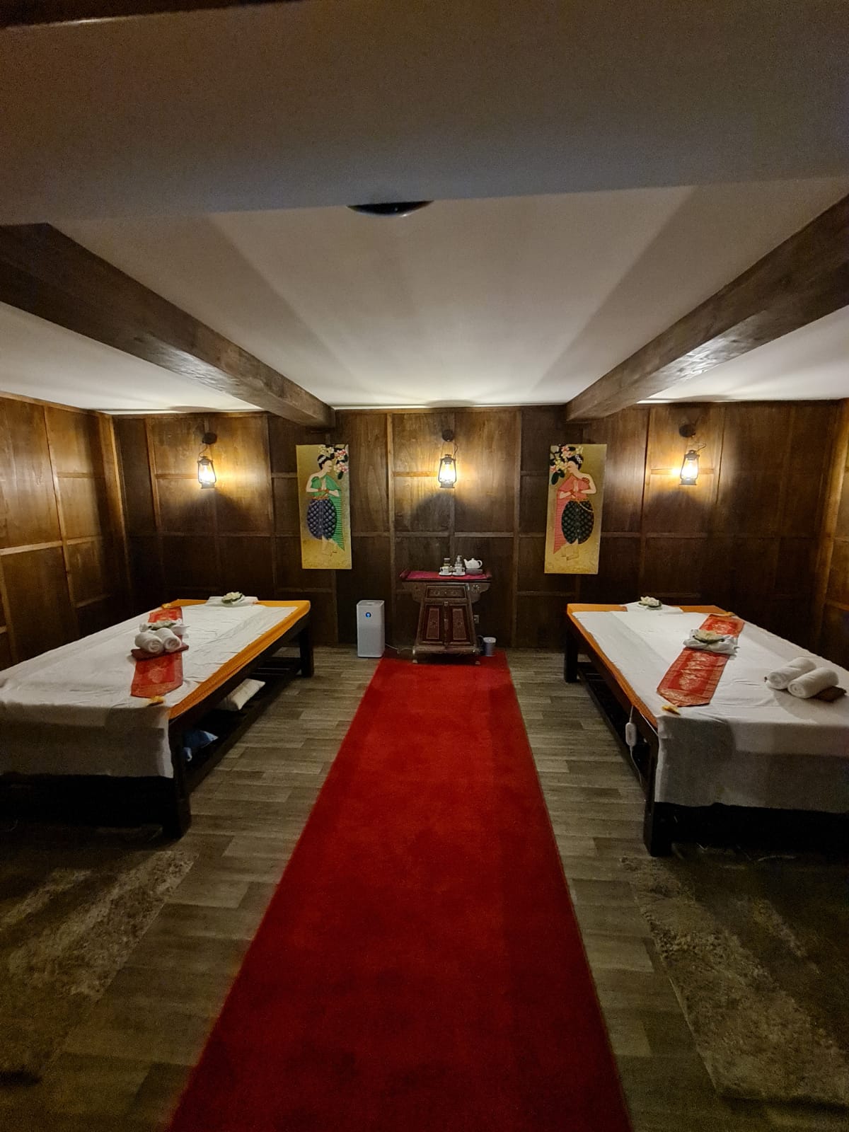 Ein Raum mit zwei Massageliegen und einem roten Teppich.