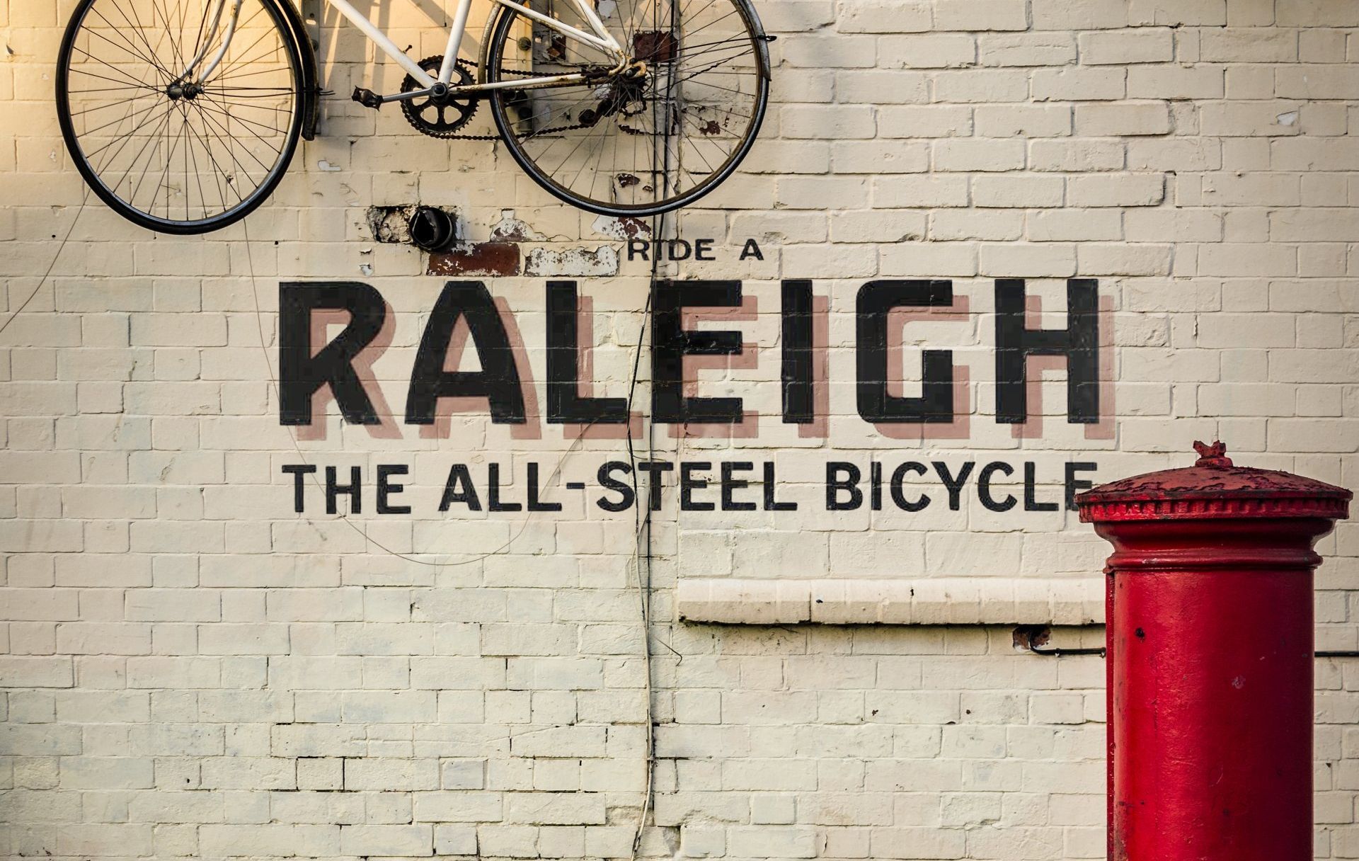 A white brick wall with the words raleigh the all steel bicycle painted on it