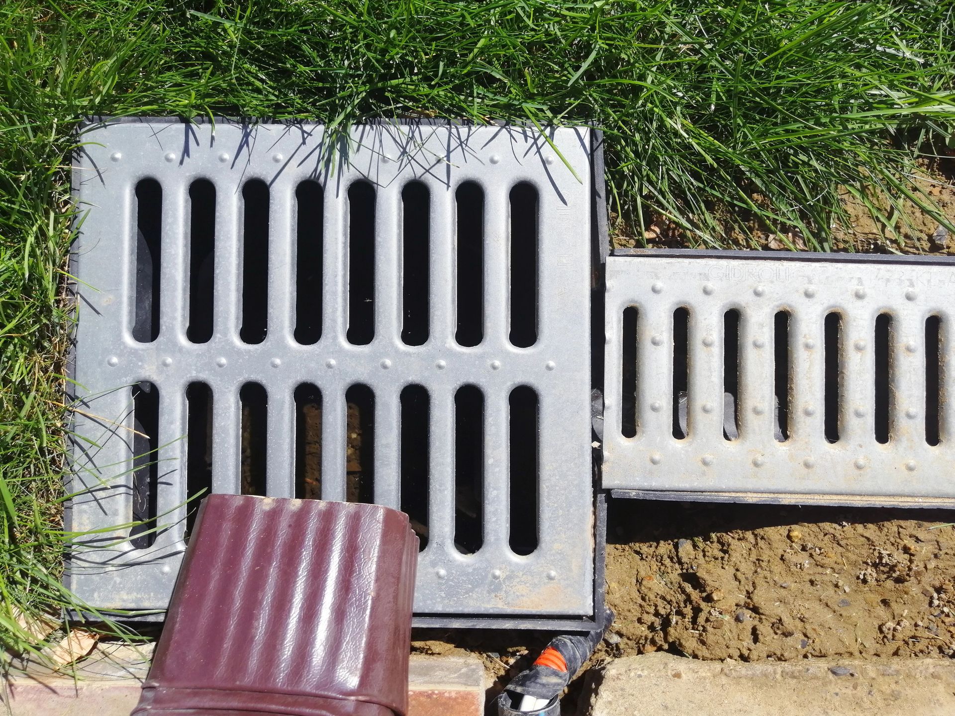 A couple of drain covers are sitting in the grass A couple of drain covers are sitting in the grass