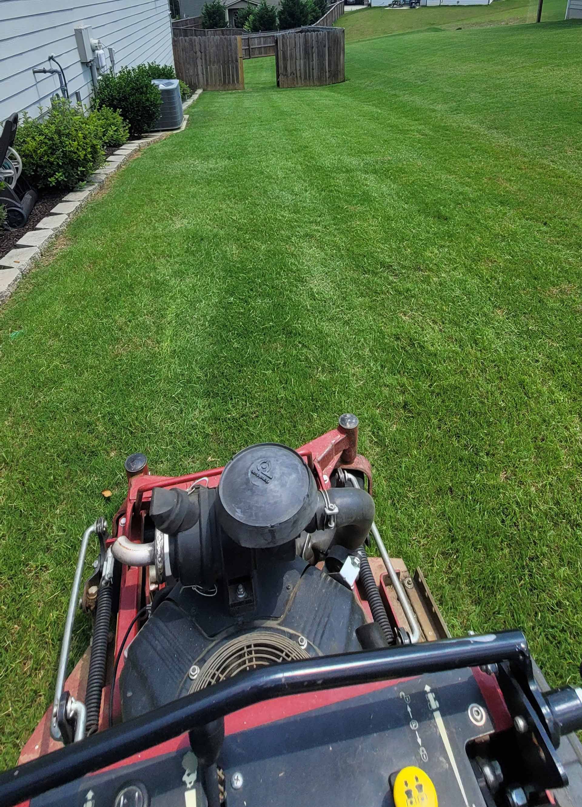 A lawn mower is cutting a lush green lawn