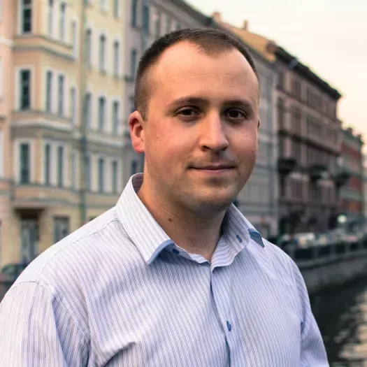 A man in a blue shirt is standing in front of a building.