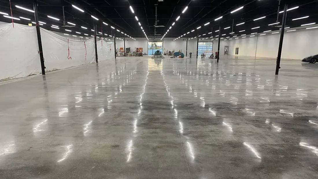A large empty warehouse with a shiny concrete floor and lots of lights.