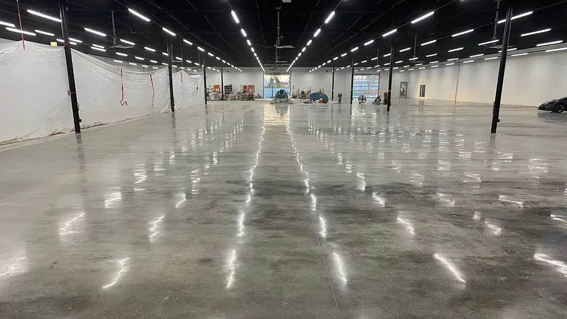 A large empty warehouse with a shiny concrete floor and lots of lights.