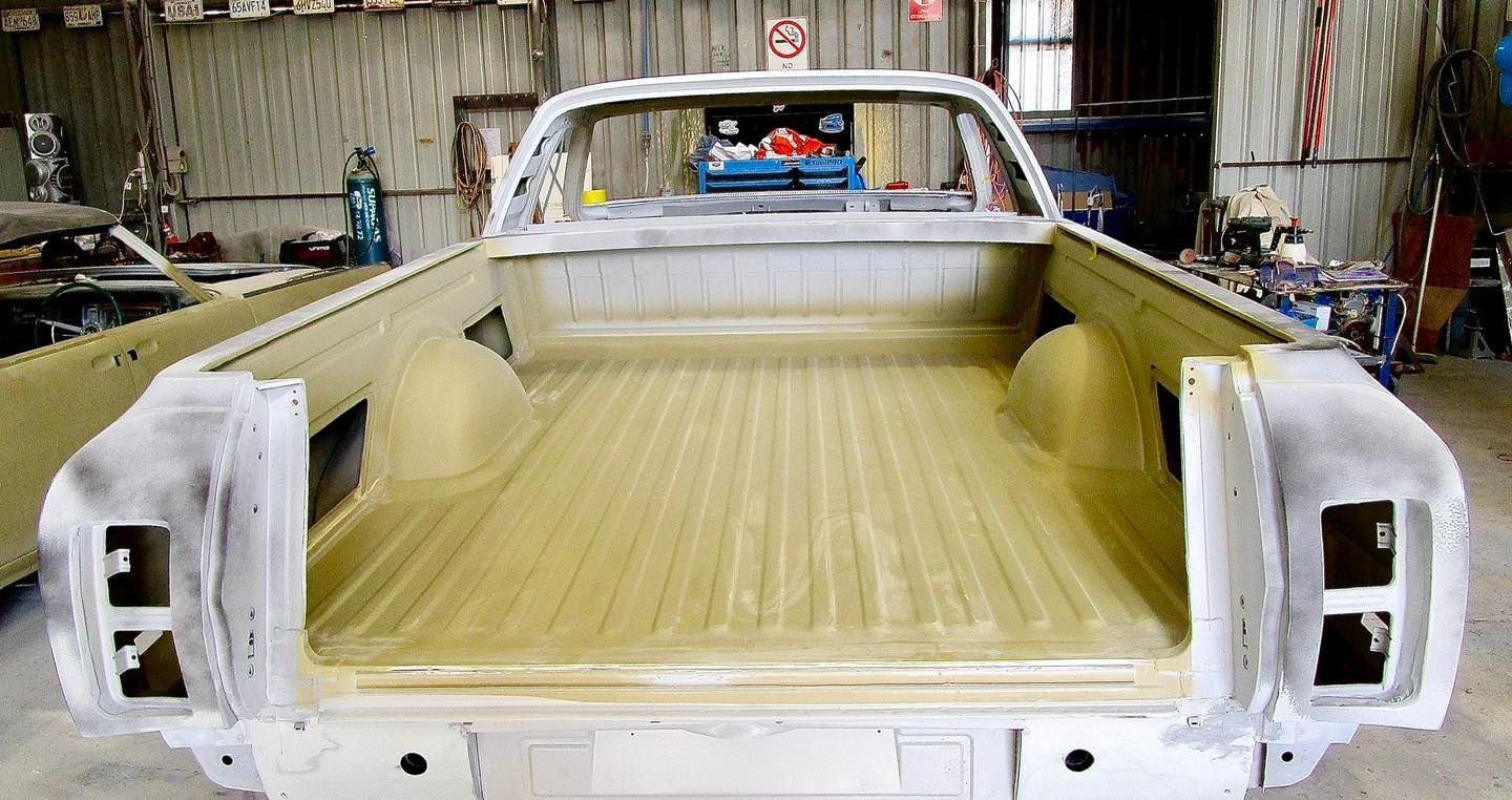 White utility vehicle truck bed in a garage, prepared for paint.