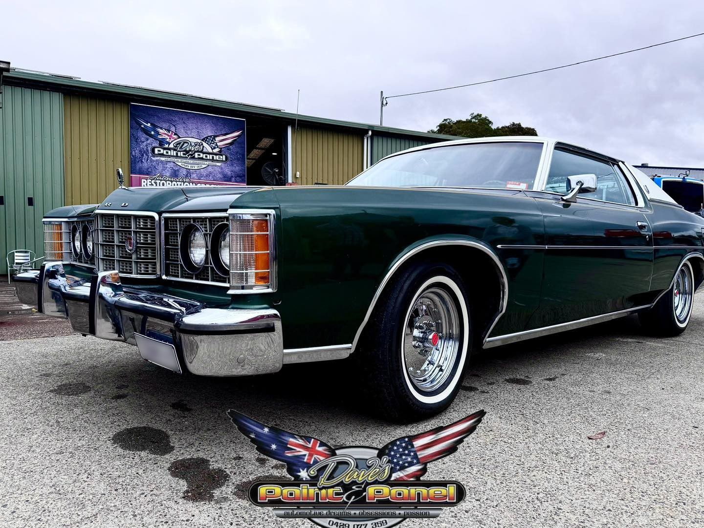Green classic car with white top, chrome trim, and wire wheels parked outside a building.