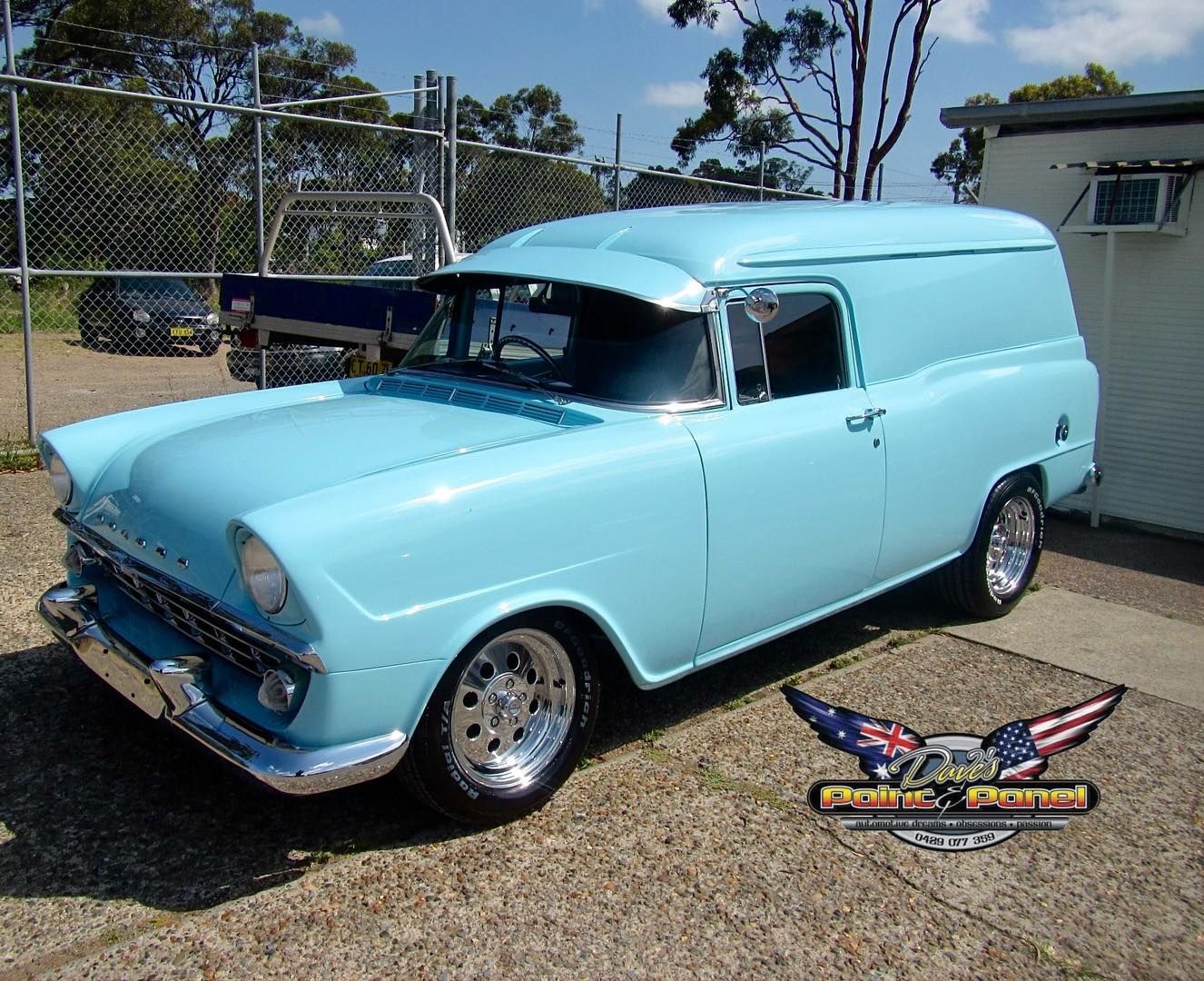 Light blue vintage panel van parked outside on a sunny day.
