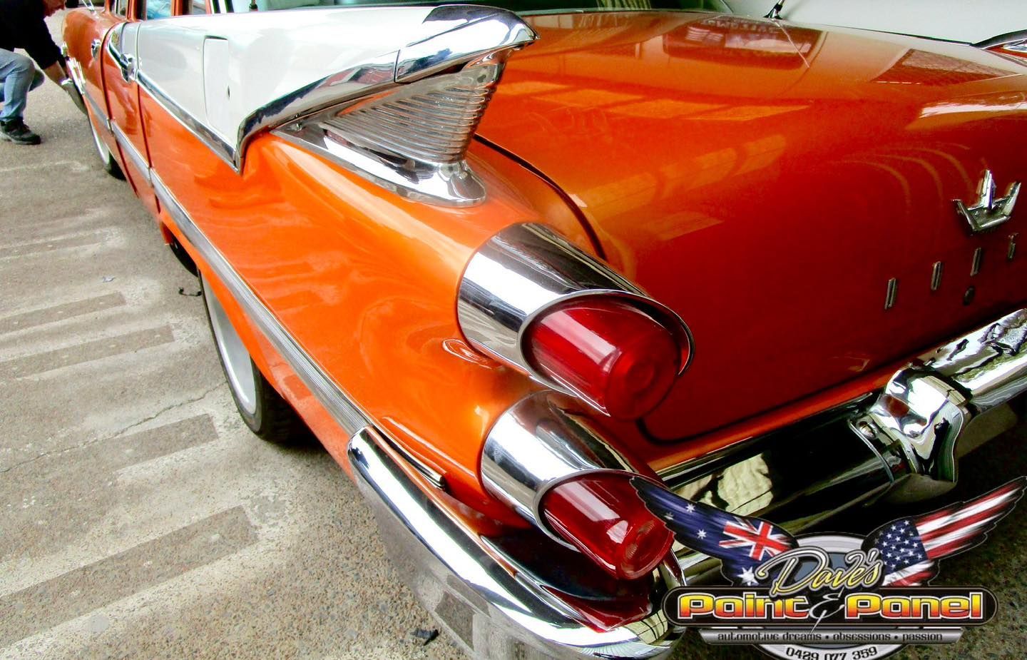 Orange vintage convertible car with chrome details and red taillights.