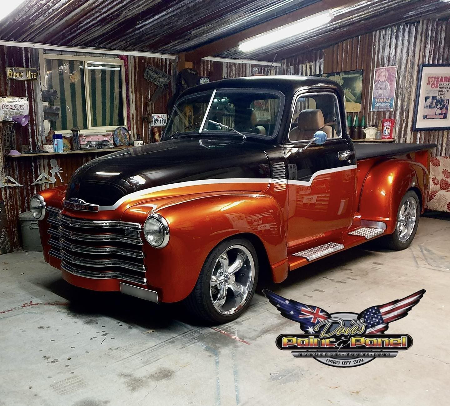 Customized black and orange Chevrolet pickup truck in a garage with chrome accents.