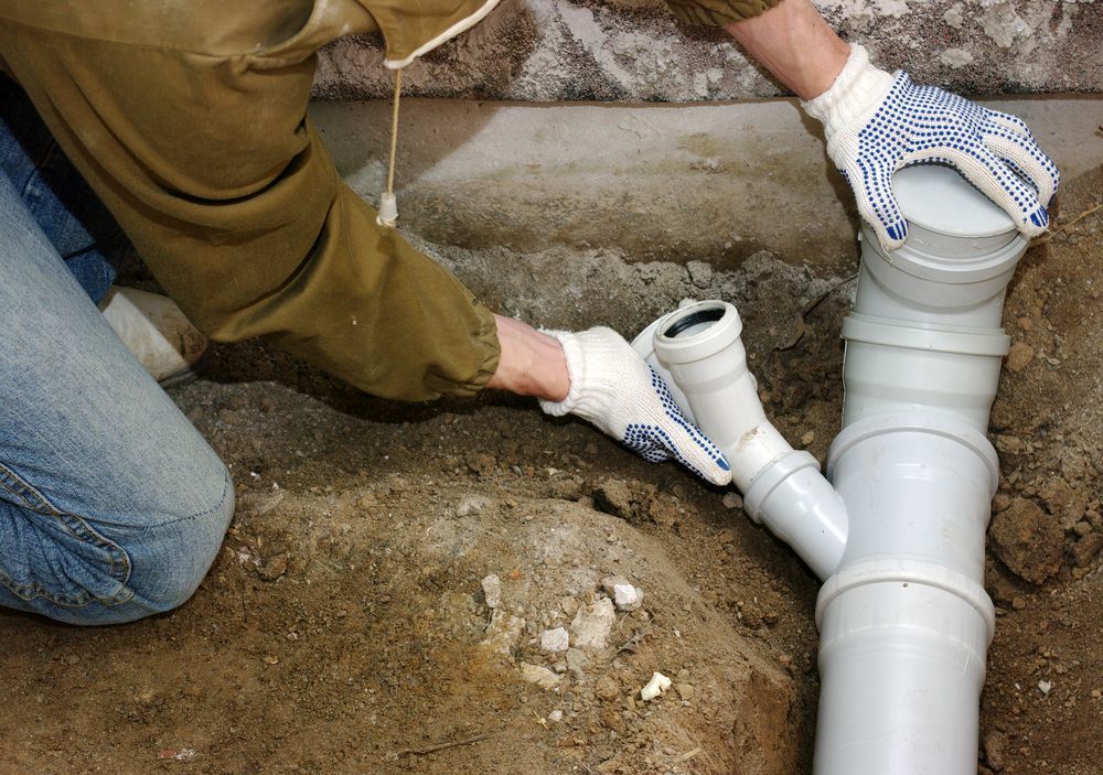 a person is installing a sewer pipe in the ground