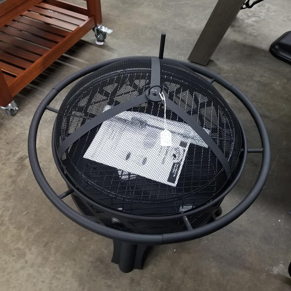 A black fire pit is sitting on a concrete floor