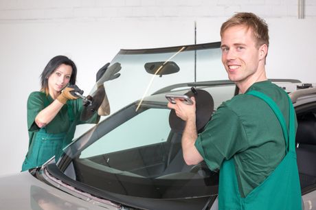 man and woman installing car windshield