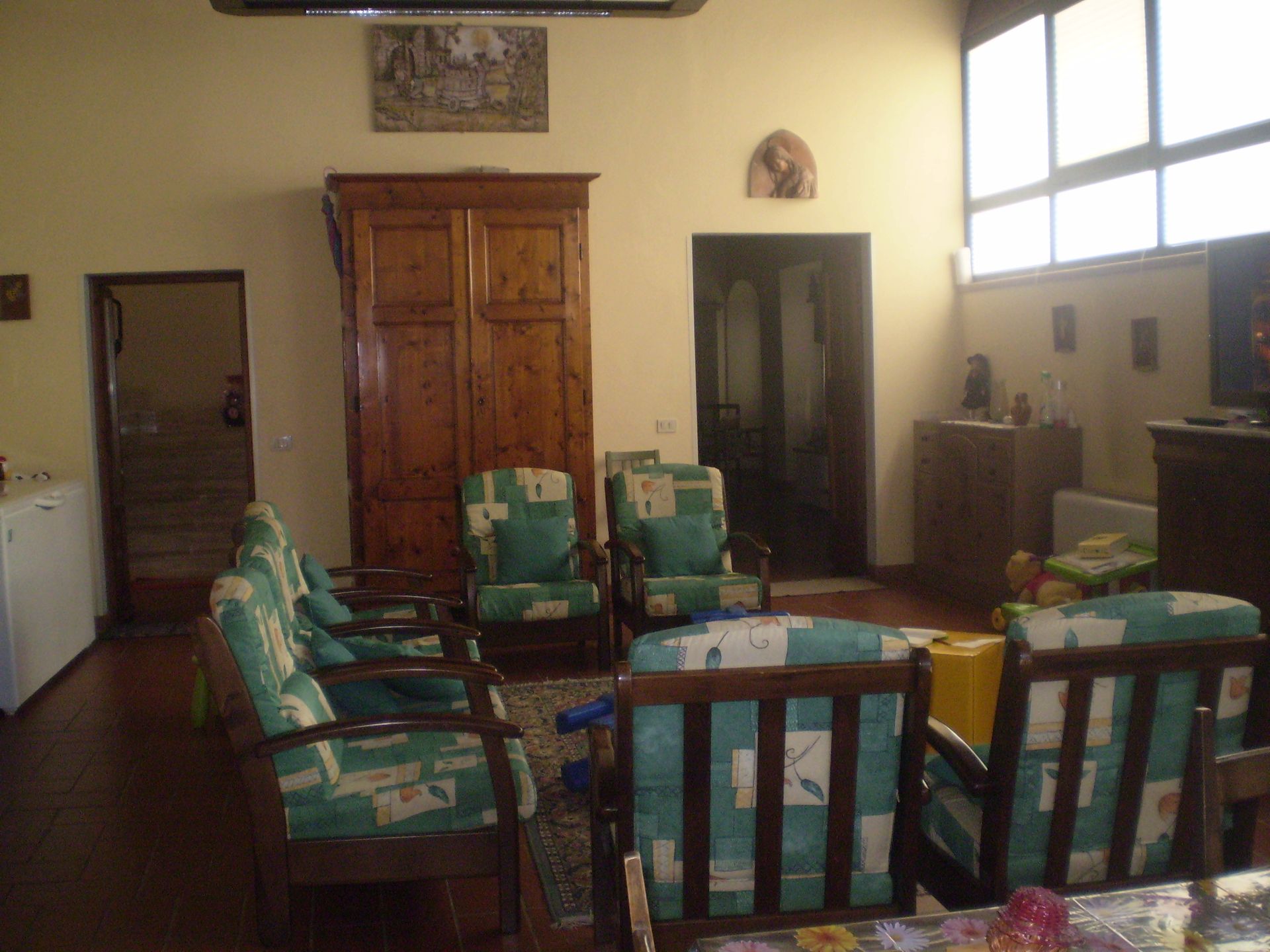 Soggiorno con mobili in legno, tra cui sedie con cuscini a fantasia verde.