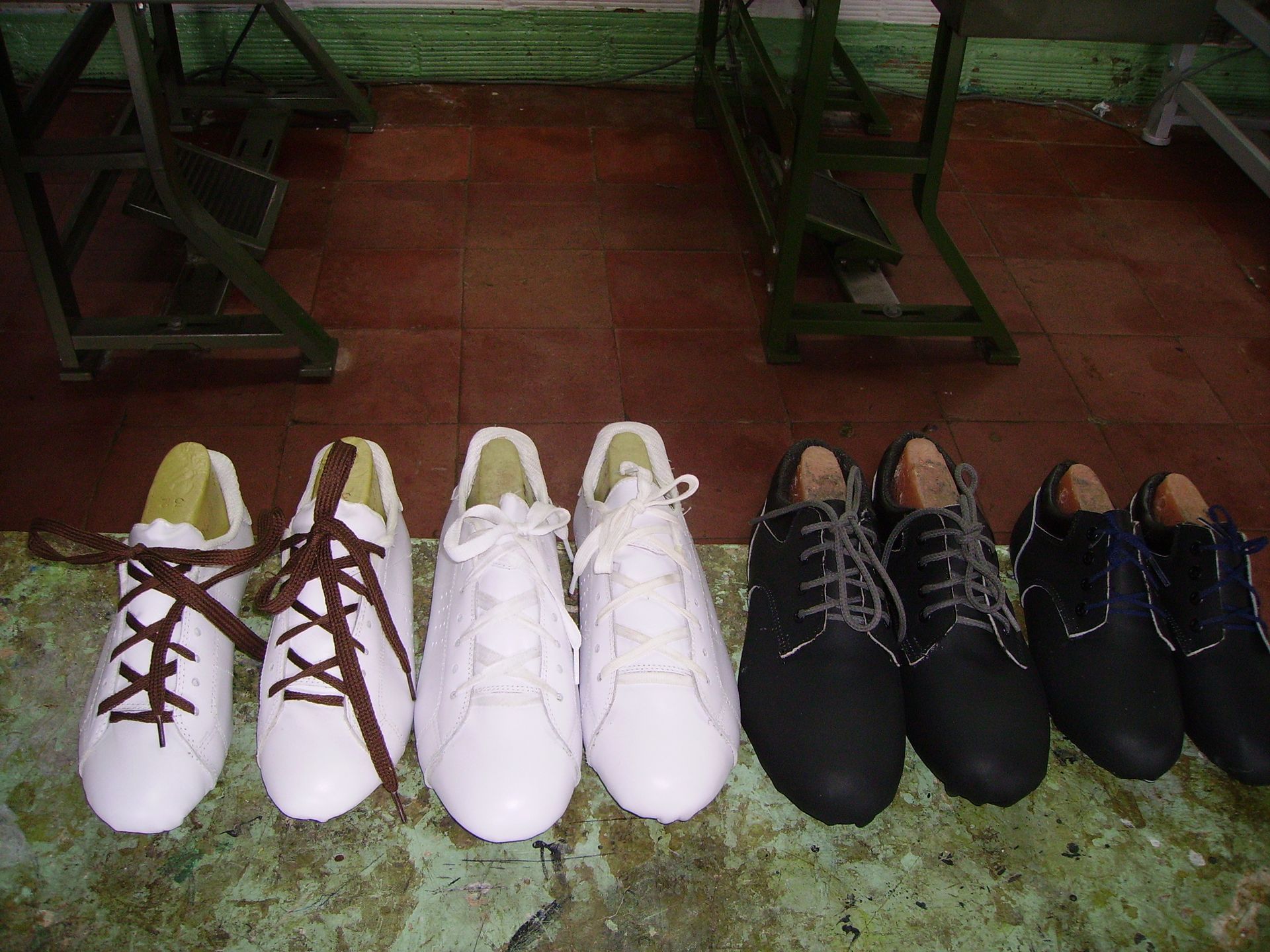 Una fila di scarpe da ginnastica e scarpe eleganti di vari colori su un pavimento verde.