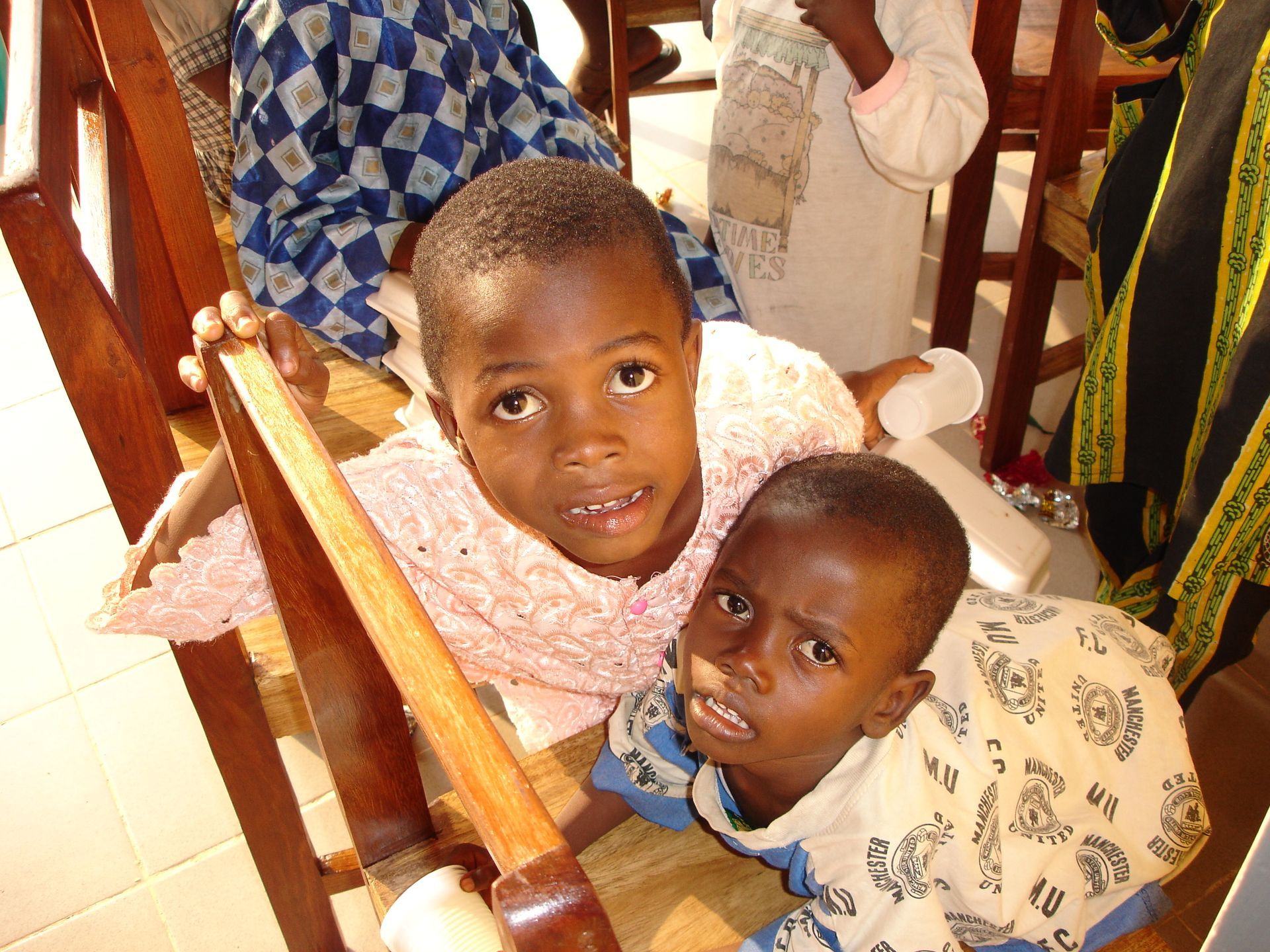Due bambini appoggiati a una ringhiera di legno. Uno indossa una maglietta rosa, l'altro una fantasia; entrambi guardano verso l'alto.