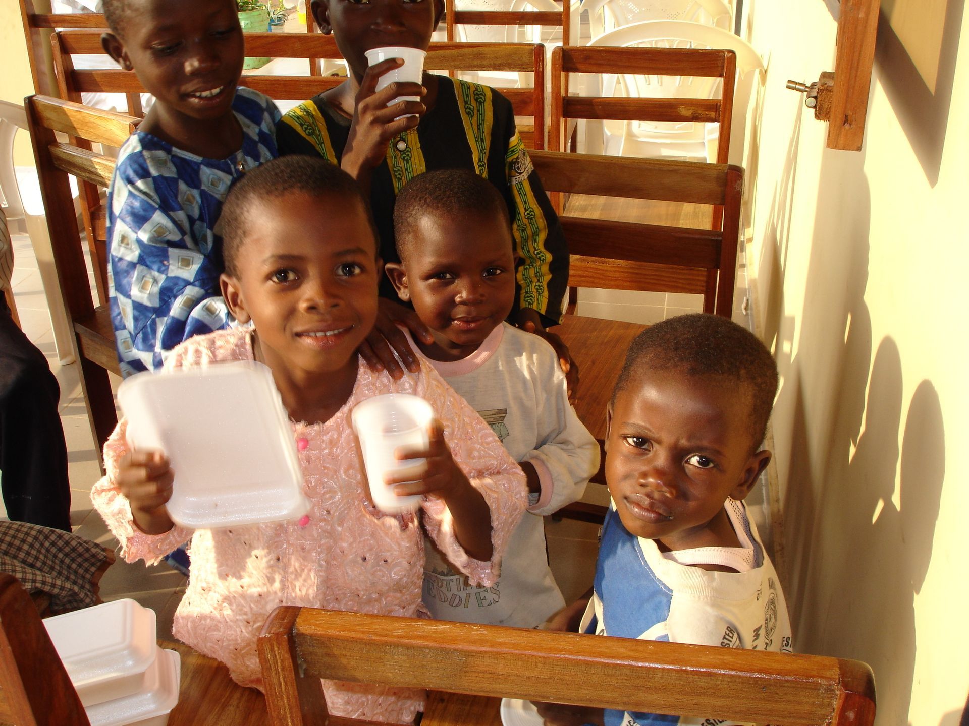 Bambini riuniti in casa, sorridenti, con in mano tazze e piatti.