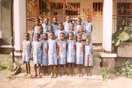 Gruppo di bambini con abiti blu coordinati in piedi davanti a un edificio.