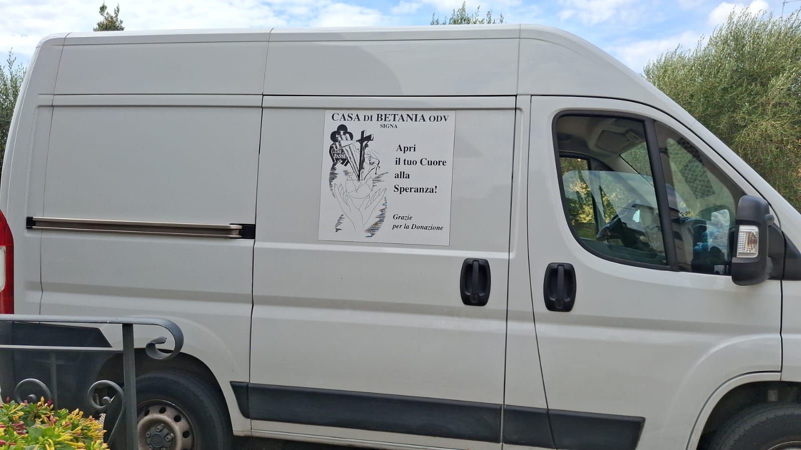 Furgone bianco con un poster sul lato. Il poster presenta una foto con del testo sottostante.