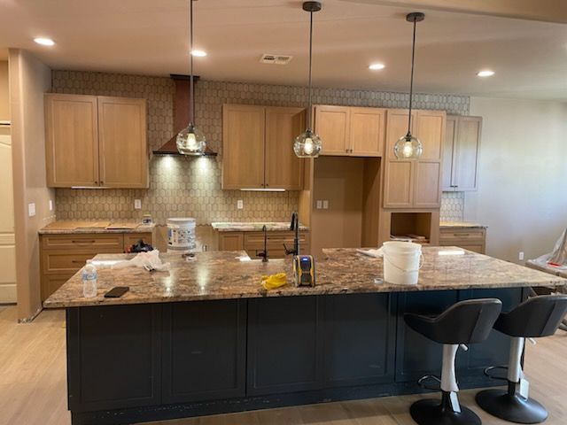 A kitchen with a large island and stools in it.