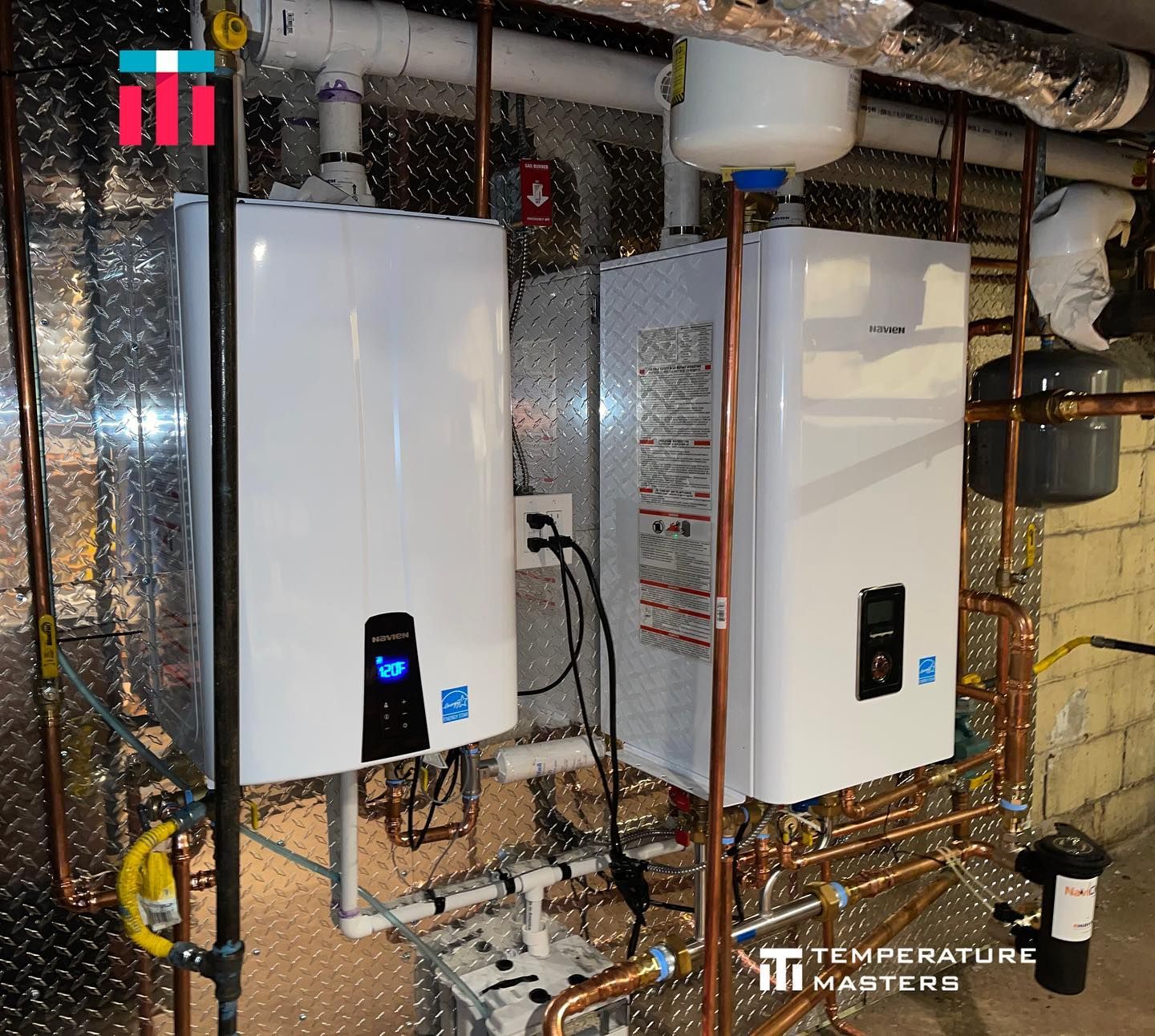 Two water heaters are sitting next to each other in a basement.