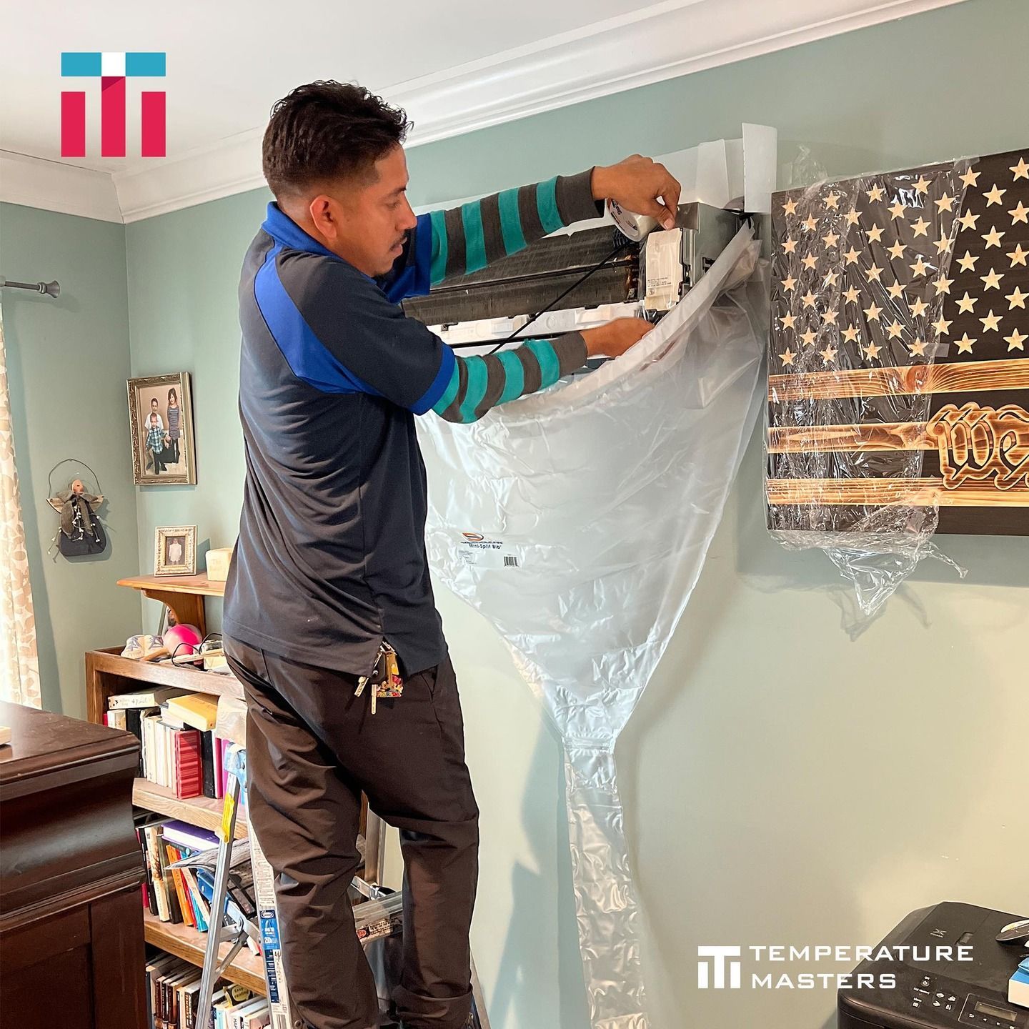 A man is cleaning an air conditioner with a plastic bag.