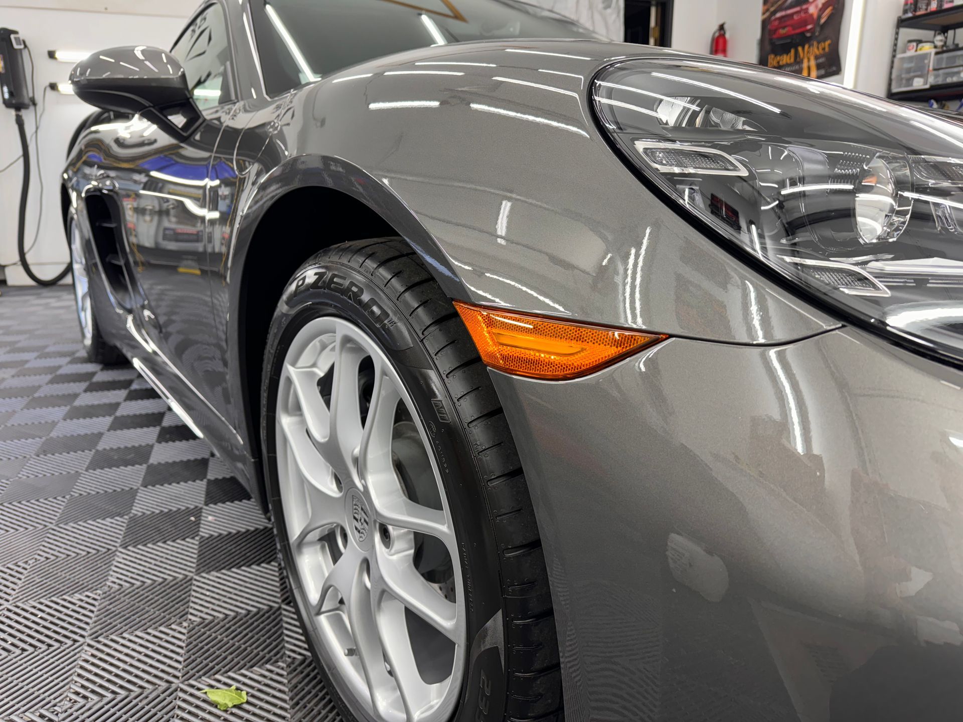 A gray porsche boxster is parked in a garage.