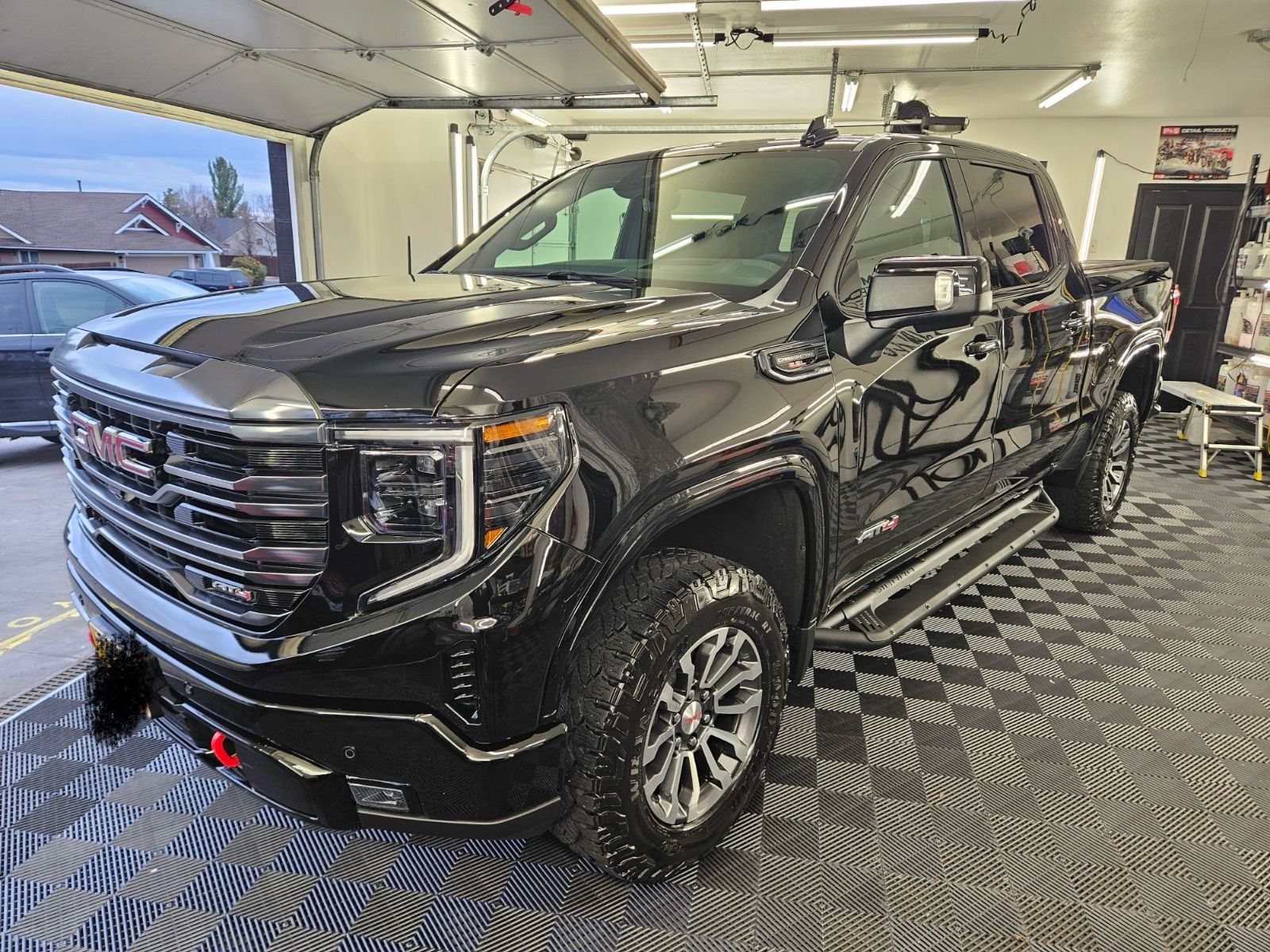 A black gmc sierra pickup truck is parked in a garage.