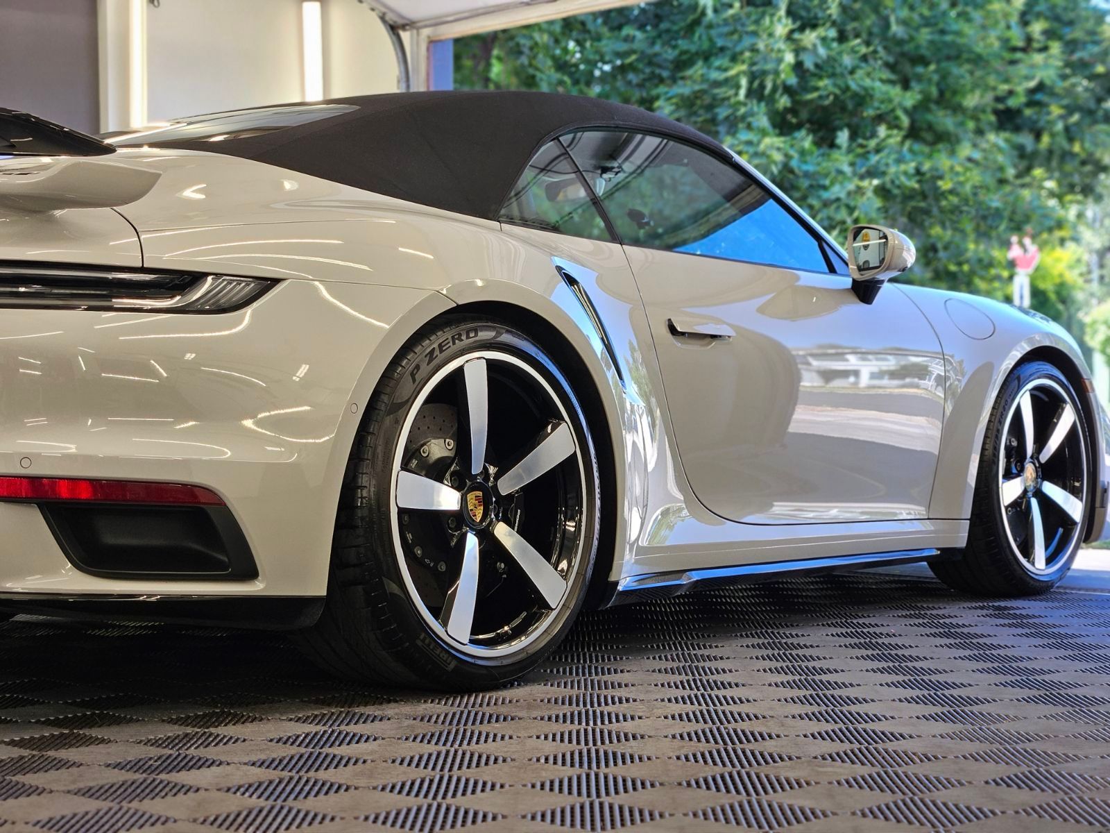 A white porsche 911 turbo cabriolet is parked in a garage.