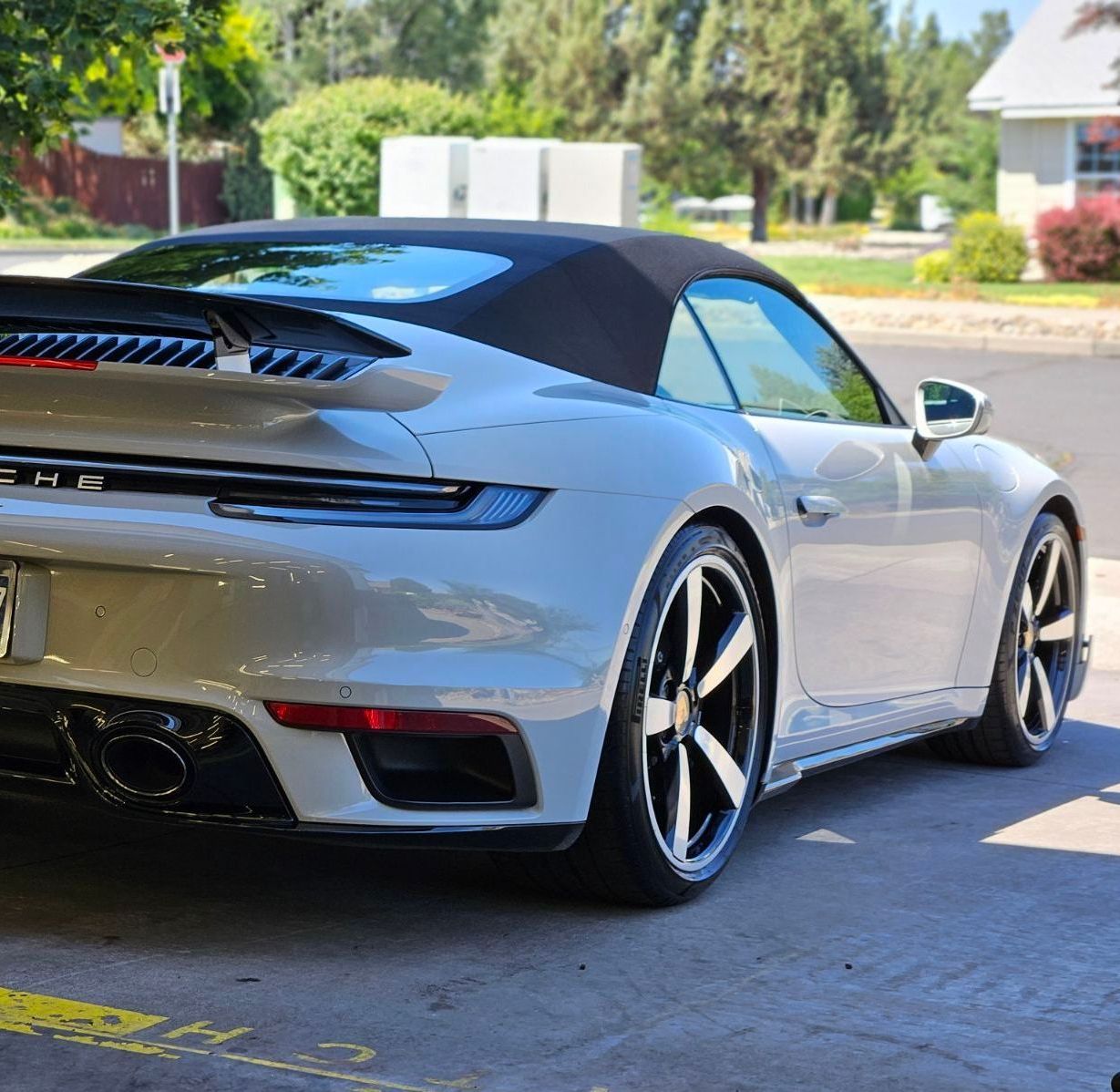 A white porsche 911 turbo convertible is parked in a parking lot.