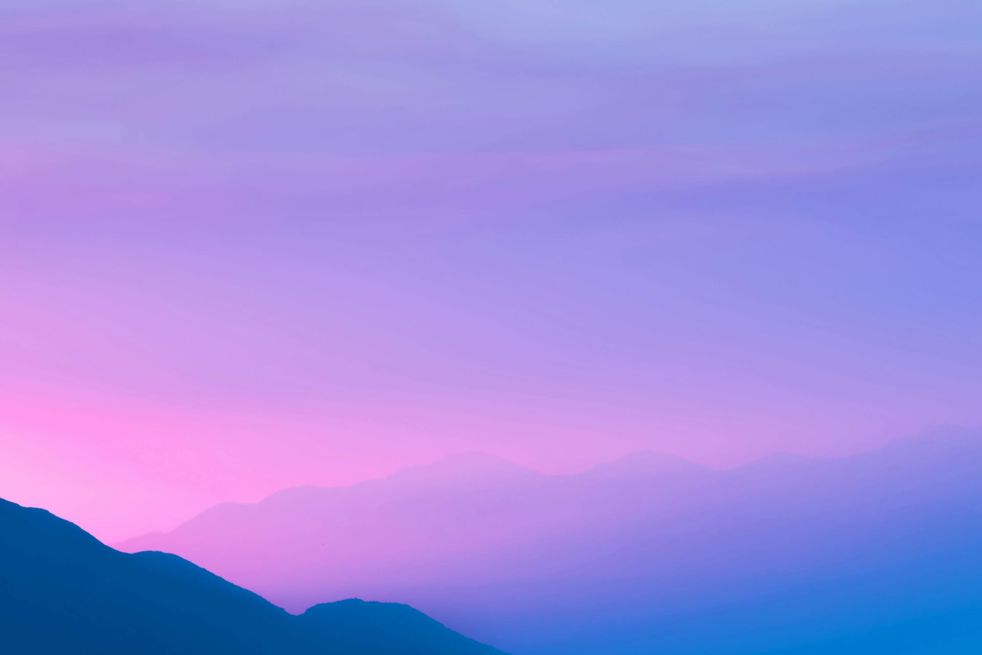 A mountain silhouetted against a pink and purple sky at sunset.